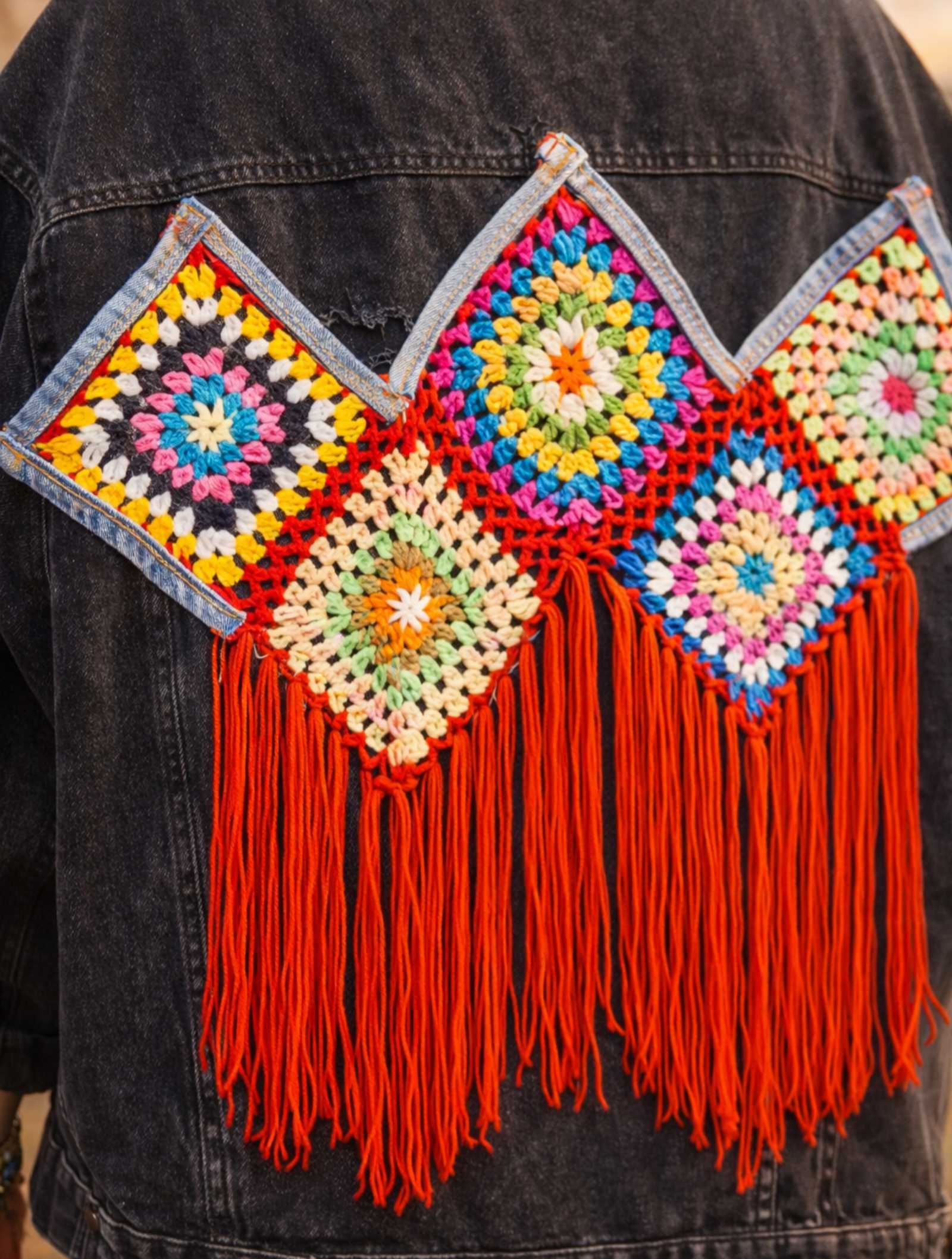 Detail van handgemaakt crochet patchwork met franjes op upcycled denim jasje