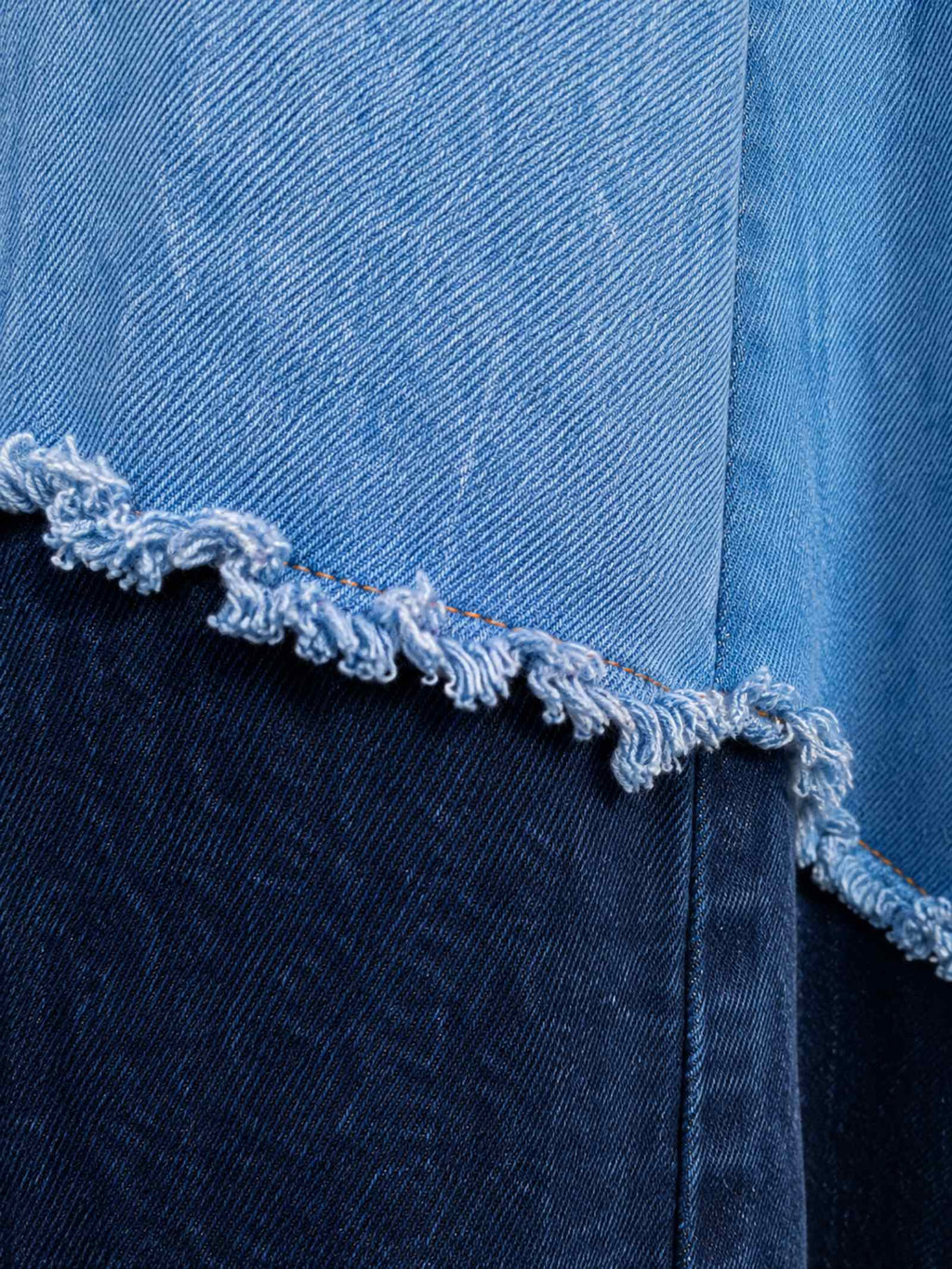 Detail van handgemaakte rafelnaad tussen lichtblauwe en donkerblauwe denimlagen