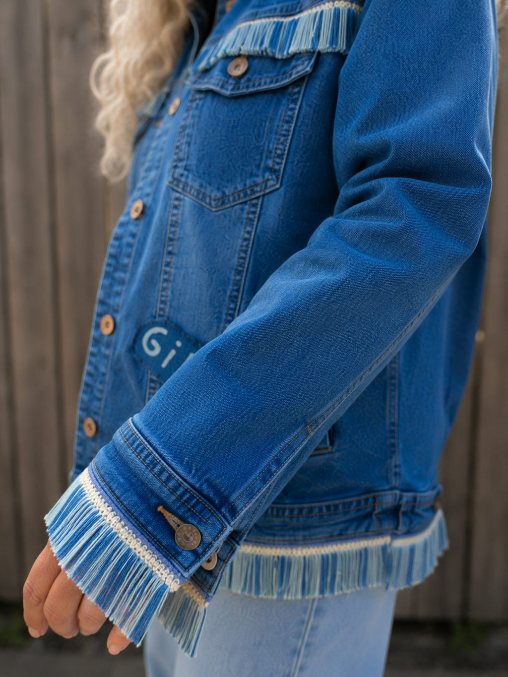 Detail van handgemaakte franje aan de mouw van een One of a Kind upcycled denim jasje