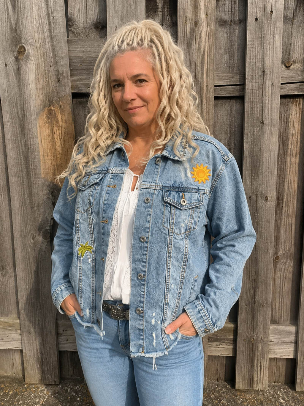 Vrouw draagt handgemaakt upcycled denim jasje Free Spirit met zon- en palmboomdetails van Old New Atelier, one of a kind spijkerjasje.