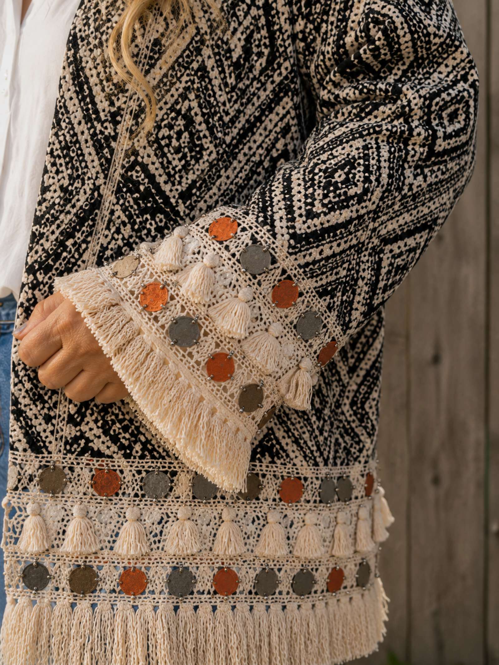 Detail van de franjes, muntjes en gehaakte afwerking van het boho kimono jasje.