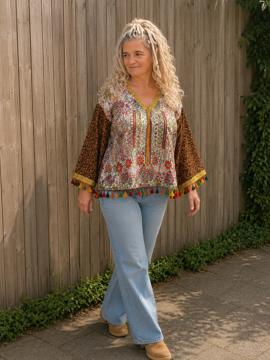 Boho bloemenblouse gedragen tijdens een wandeling met kleurrijke kwastjes