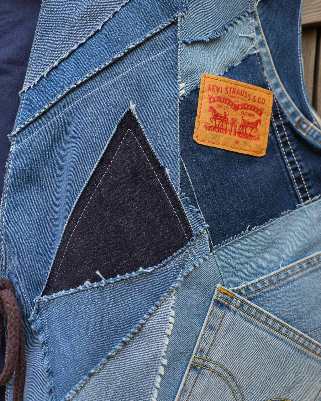Close-up van het handgemaakte patchwork van gerecyclede Levi's denim met rafelranden en verschillende blauwtinten.