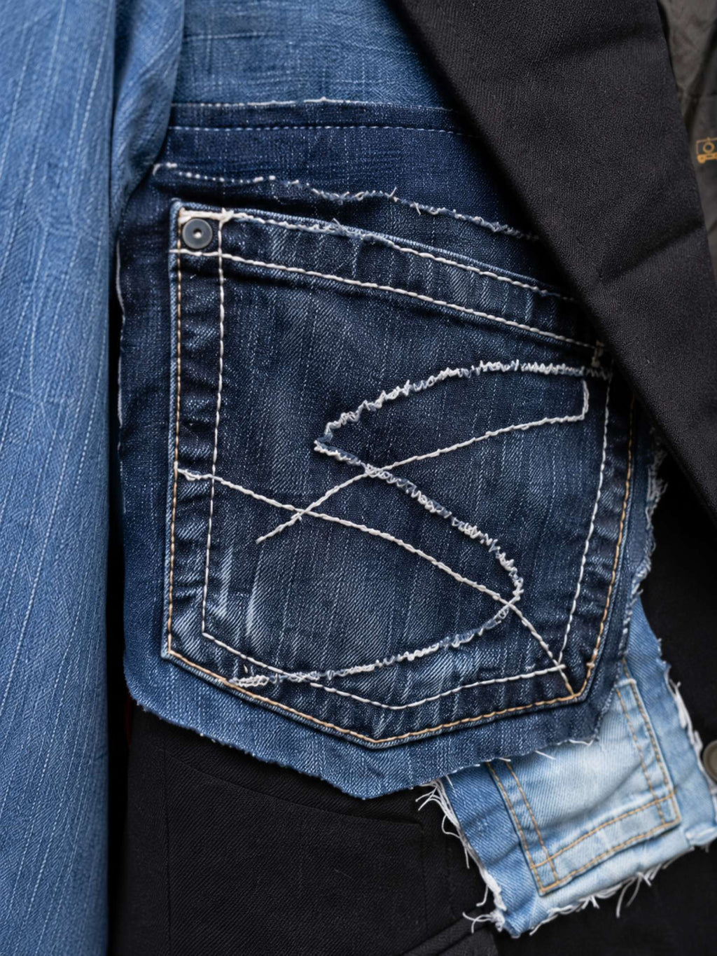 Close-up van de gerecyclede denimstructuur, jeanszak en ambachtelijk stikwerk op een upcycled colbert