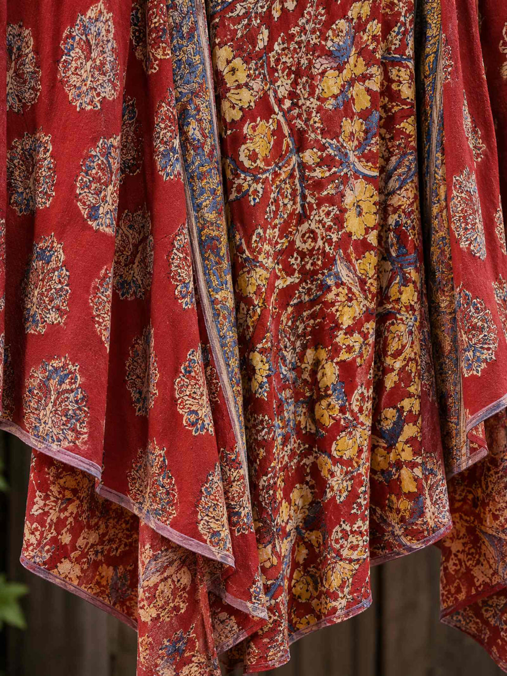 Close-up van de asymmetrische zoom en het patchworkdessin van de rode boho rok met vloeiende stof.