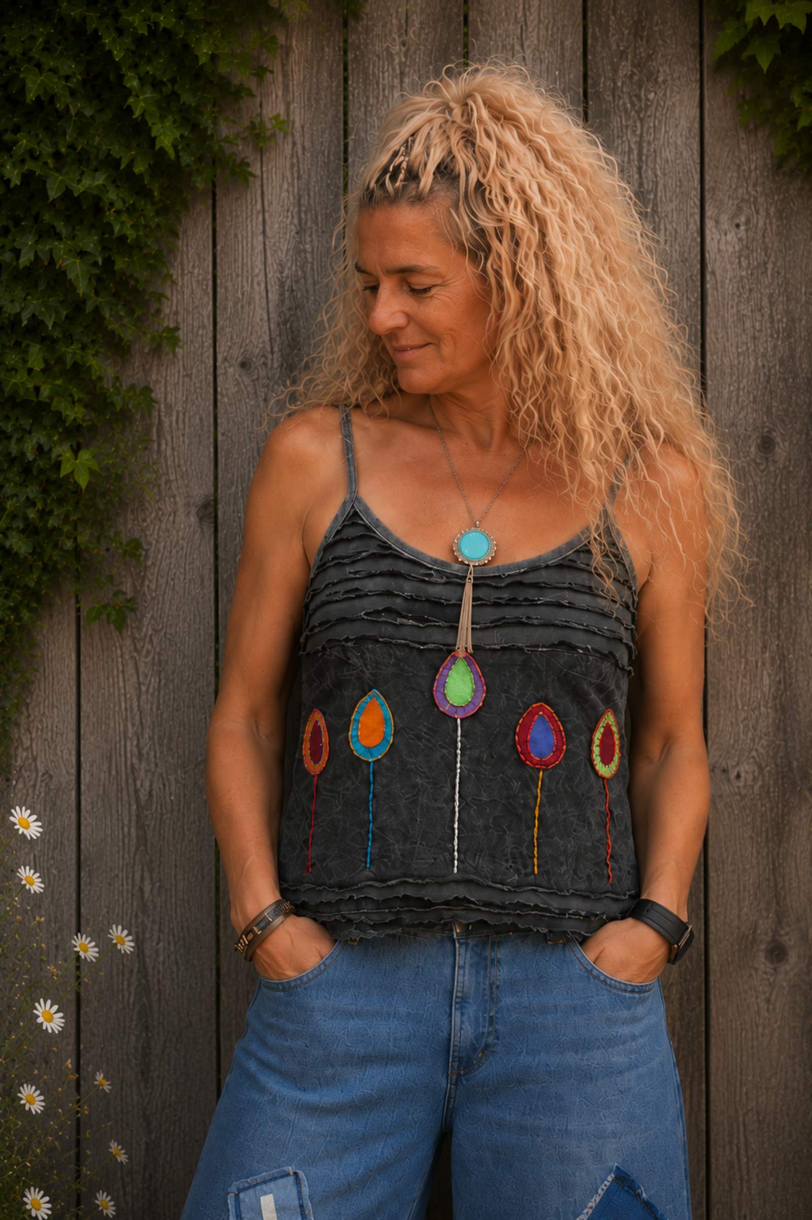 Grijs handgemaakt boho topje gedragen met kleurrijke applicaties en rafeldetails, close-up van de voorkant.