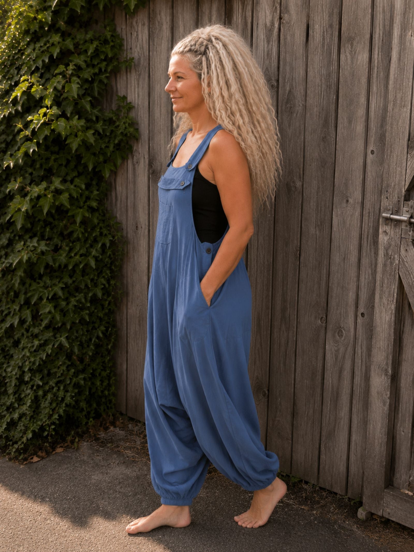 Zijaanzicht van een jeansblauwe boho jumpsuit met losse oversized pasvorm en elastische broekspijpen, gedragen door model.
