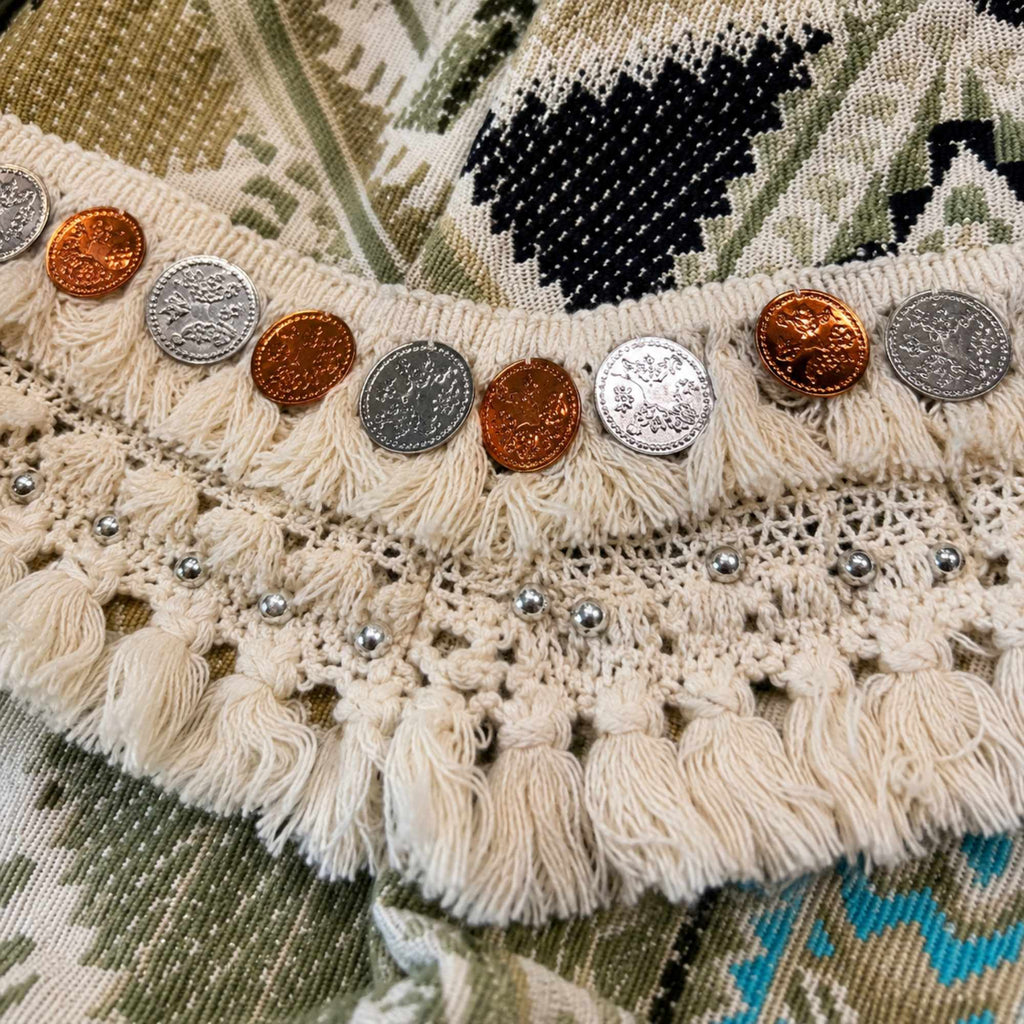 Detail van handgemaakte franjes, gehaakt kant en decoratieve metalen munten op een One of a Kind boho jasje.