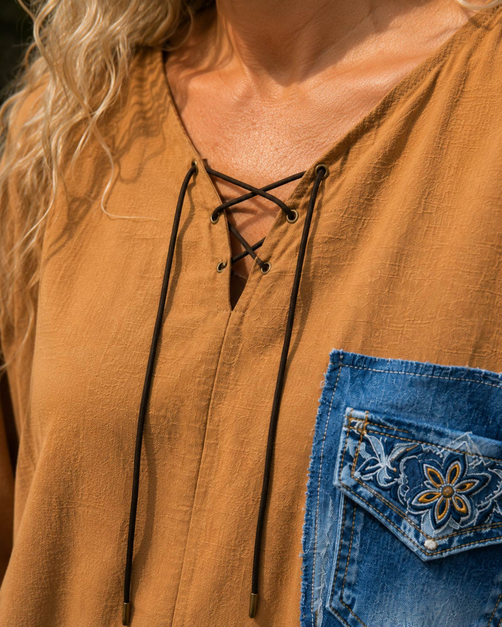 Close-up van de veterhals van de handgemaakte oversized camel blouse met denim details
