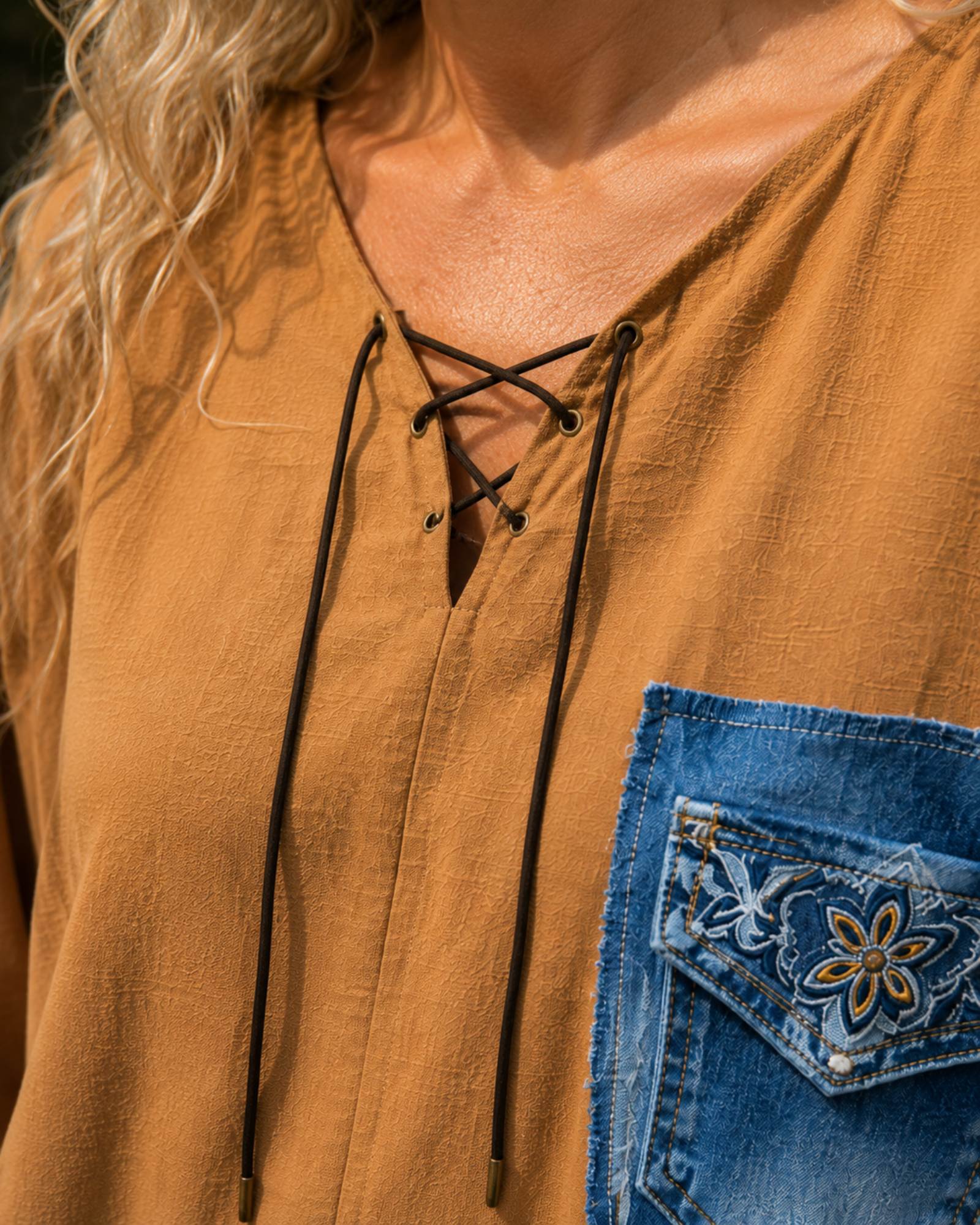 Close-up van de veterhals van de handgemaakte oversized camel blouse met denim details