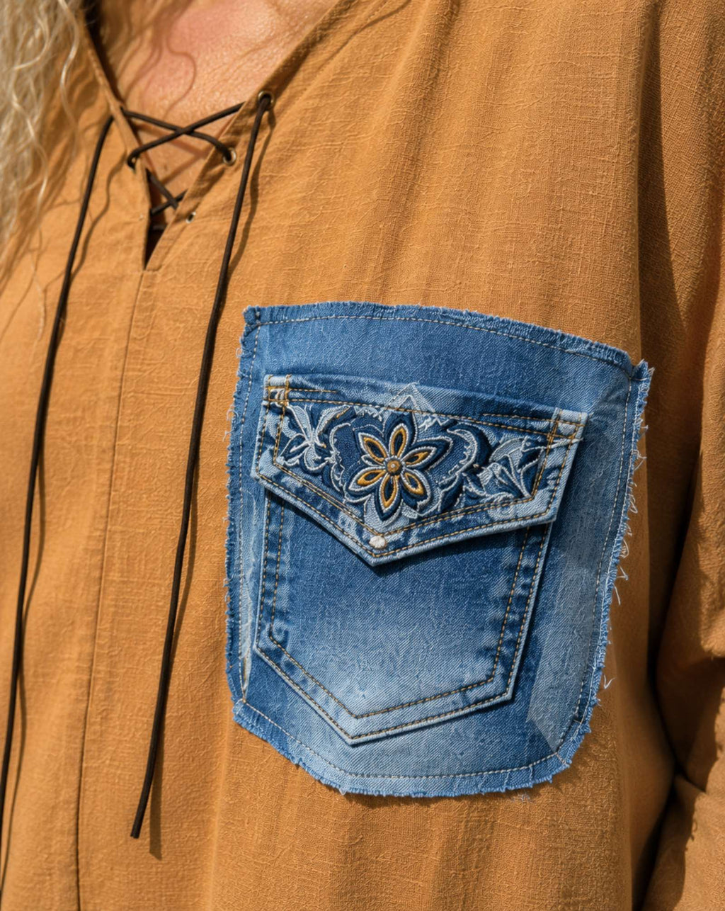 Close-up van handgemaakt upcycled denim borstzakje op oversized camel blouse