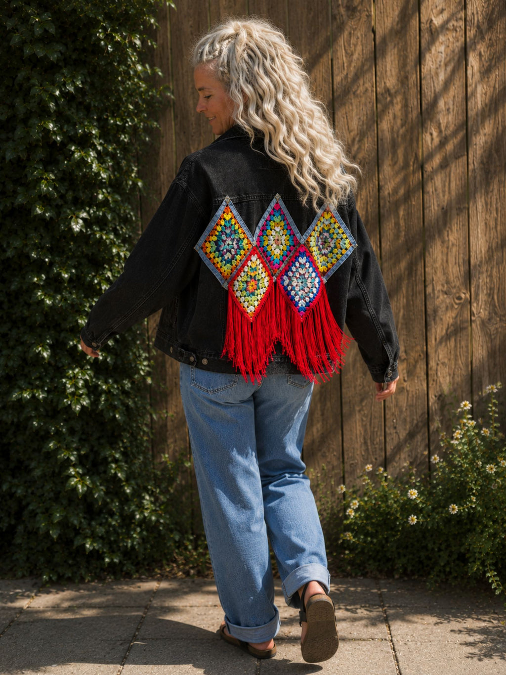 One of a Kind zwart denim jasje met bewegende rode franjes tijdens het lopen.