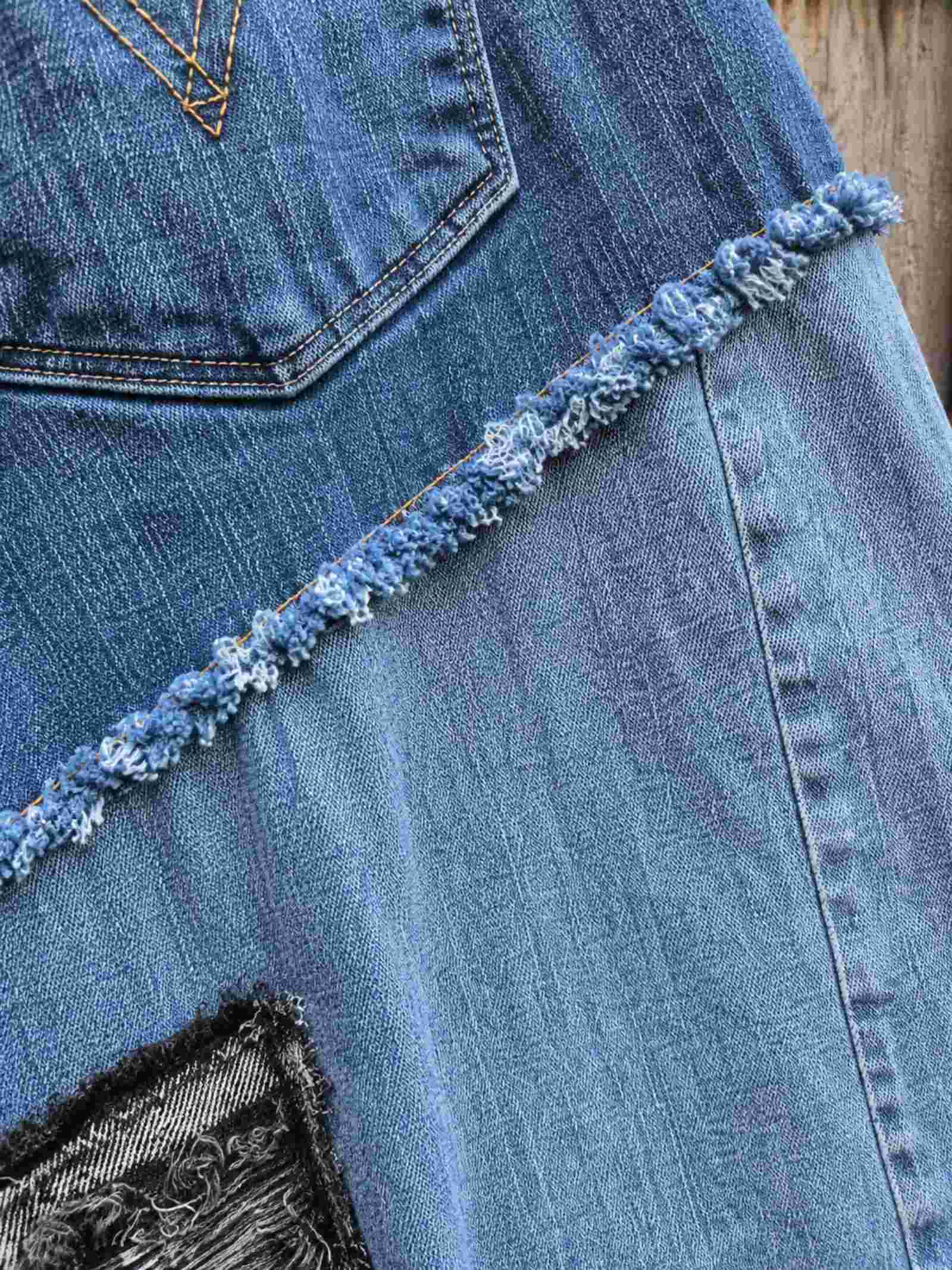 Close-up van rafelnaad en patchwork constructie op upcycled denim rok