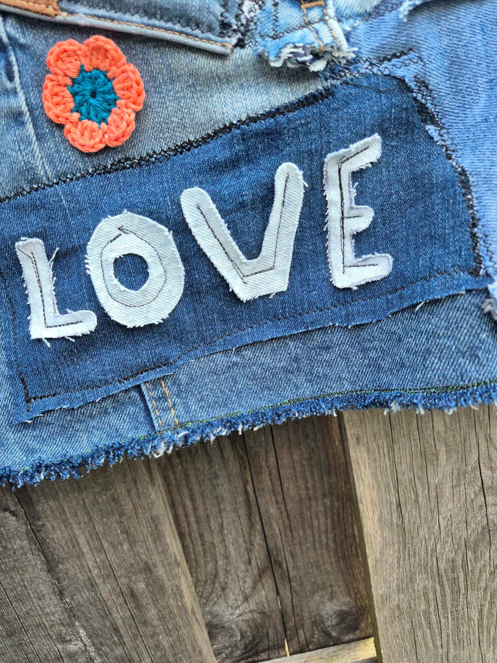 Detail upcycled denim jasje love tekst rafels