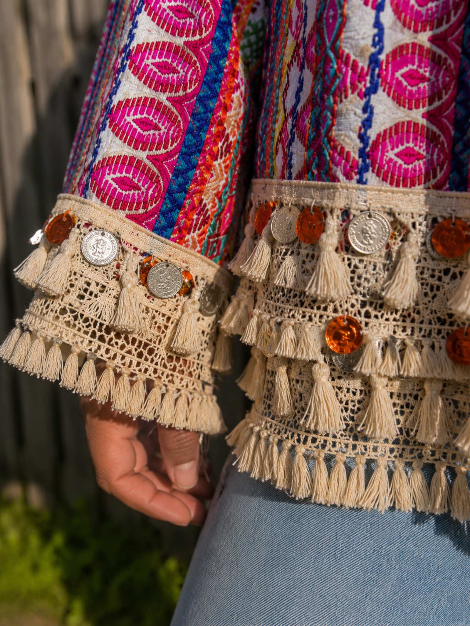 Detail van handgemaakte franjes, kant en decoratieve muntjes op One of a Kind boho jasje