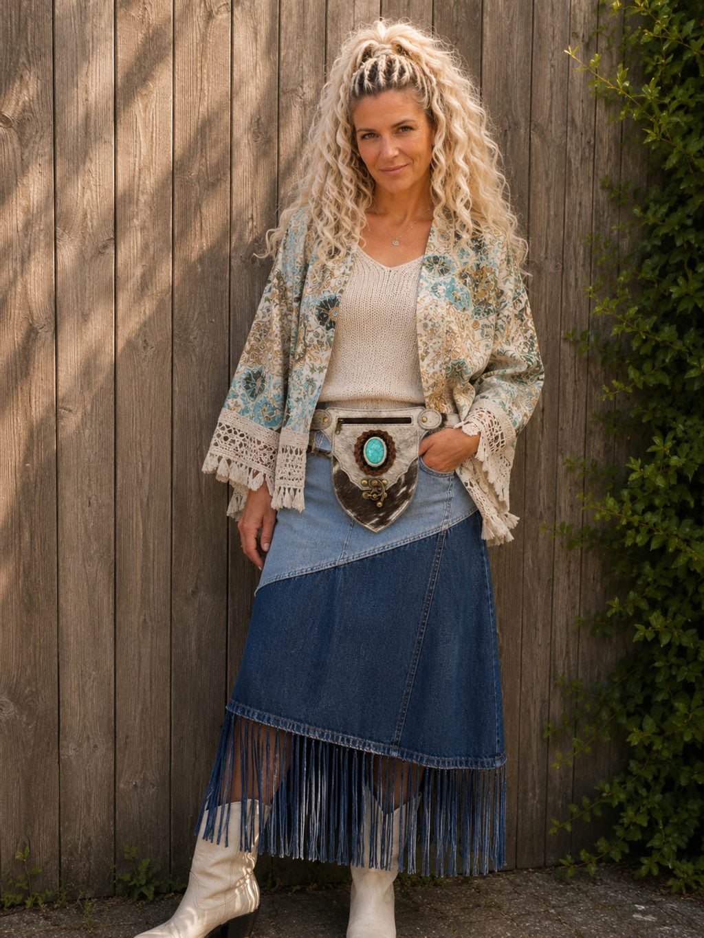 Handgemaakt boho heuptasje van koeienhuid met turquoise steen gedragen door model voor houten schutting | Old New Atelier