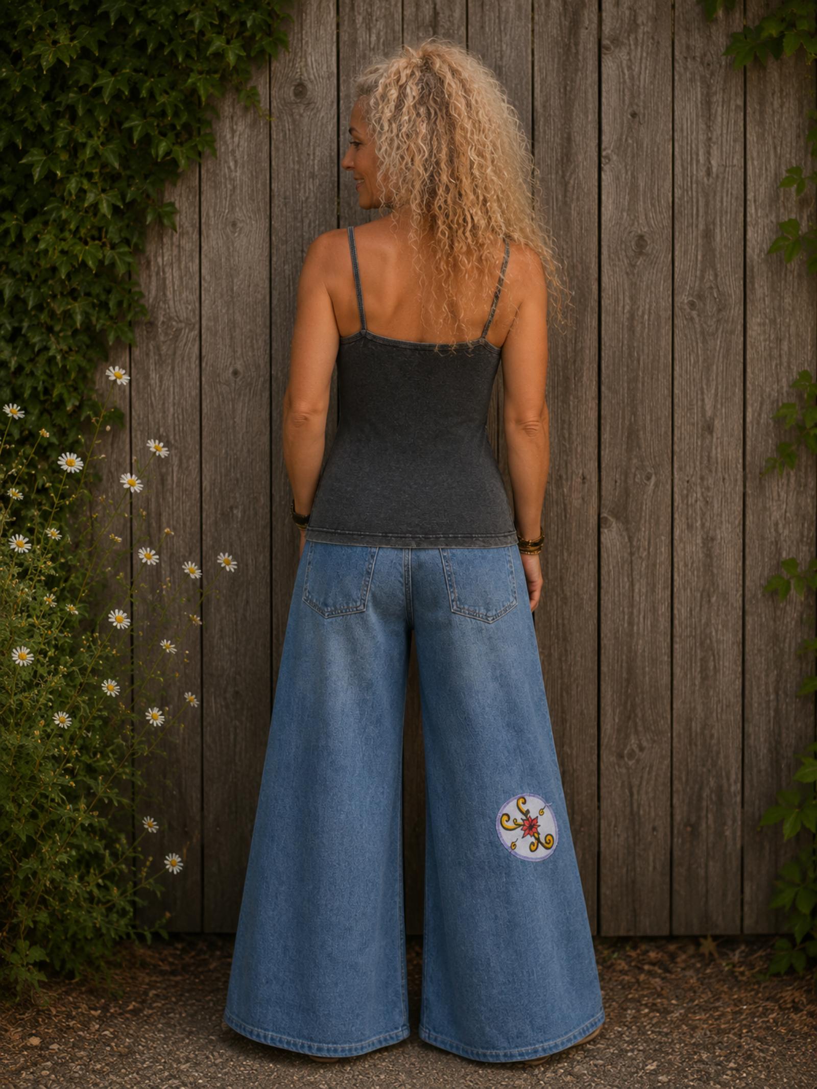 Achterkant van een grijs handgemaakt boho topje gedragen op een upcycled denim broek, met smalle schouderbandjes.