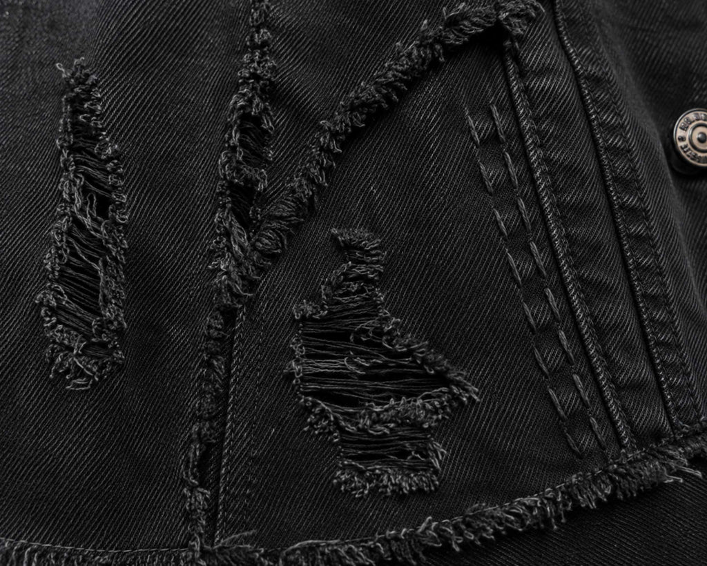 Close-up van de destroyed details in het zwarte denim jasje.