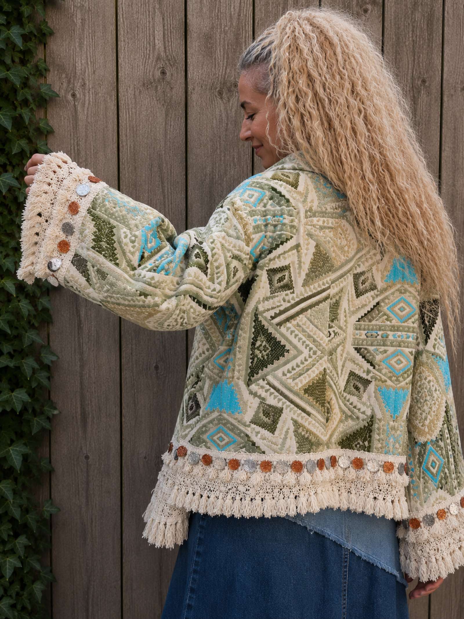 Detail van de wijde mouw met franjes, kant en metalen munten van een handgemaakt boho jasje.