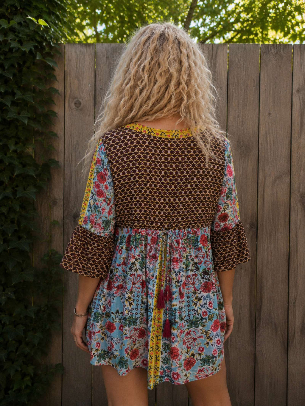 Achterkant van de boho tuniek met bloemenprint, gedragen. Rugdetail met striksluiting en luchtige katoenen stof.