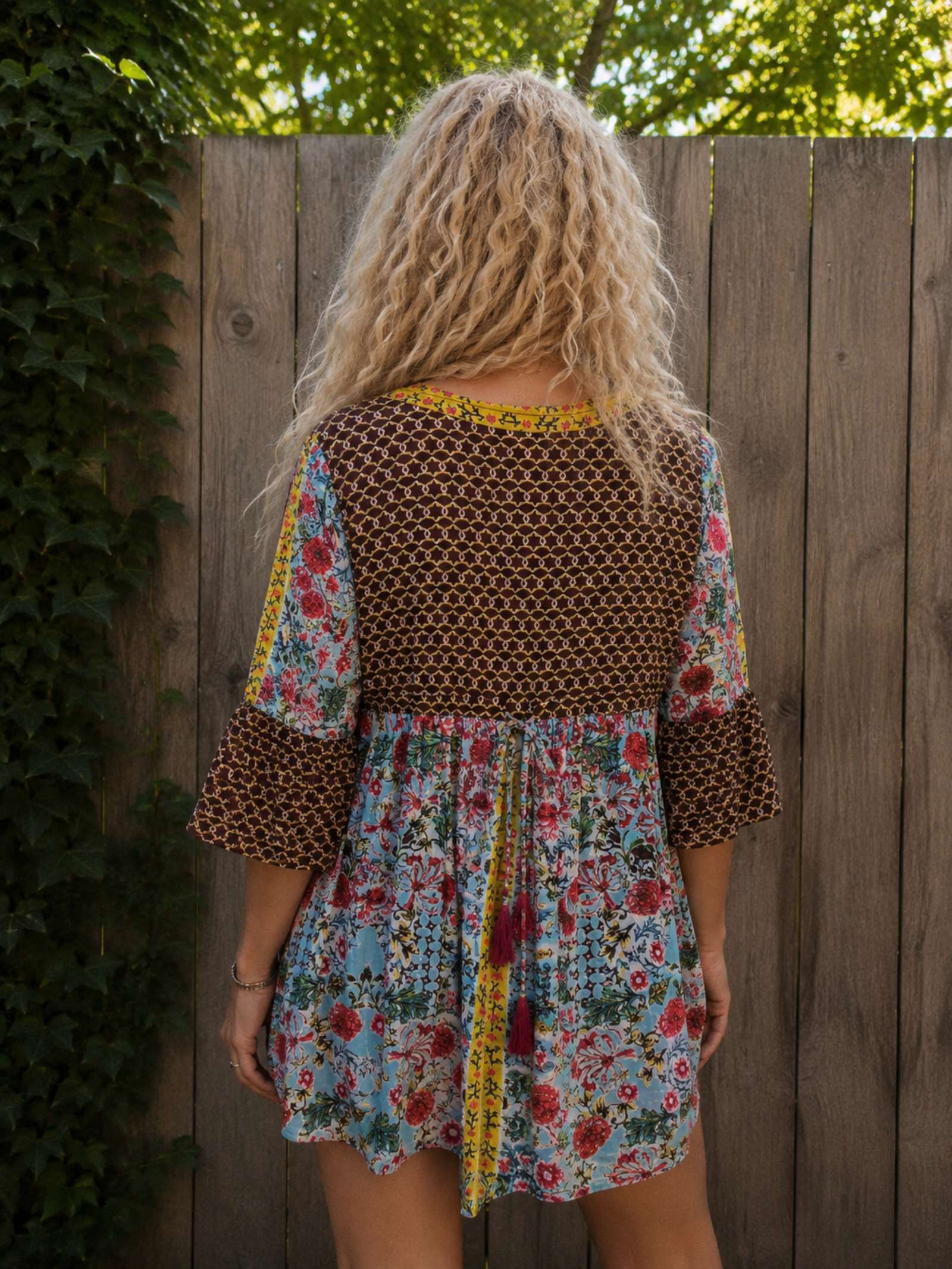 Achterkant van de boho tuniek met bloemenprint, gedragen. Rugdetail met striksluiting en luchtige katoenen stof.