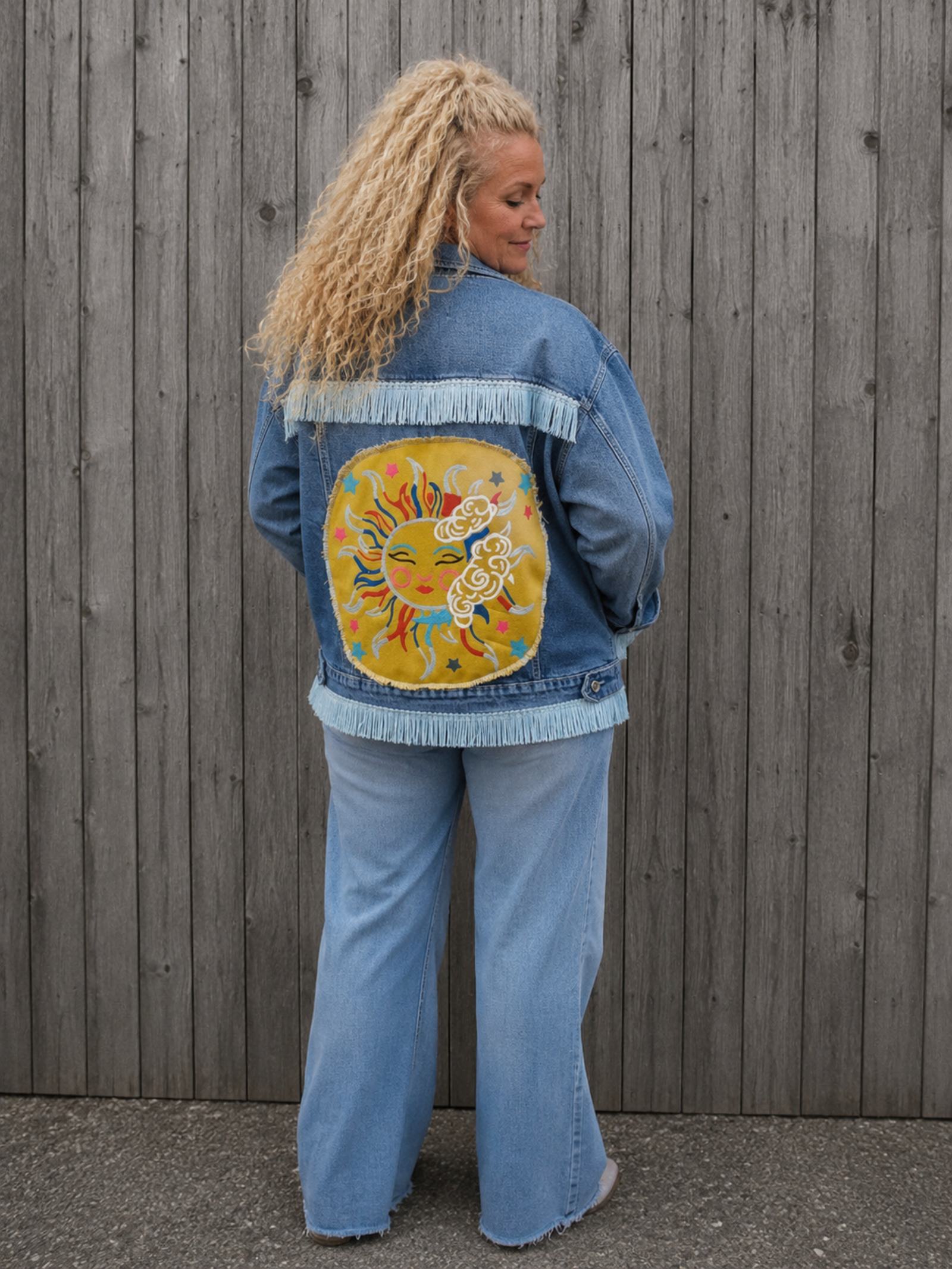 Zijaanzicht van Moon Soul denim jasje gedragen door vrouwelijk model aan houten schutting