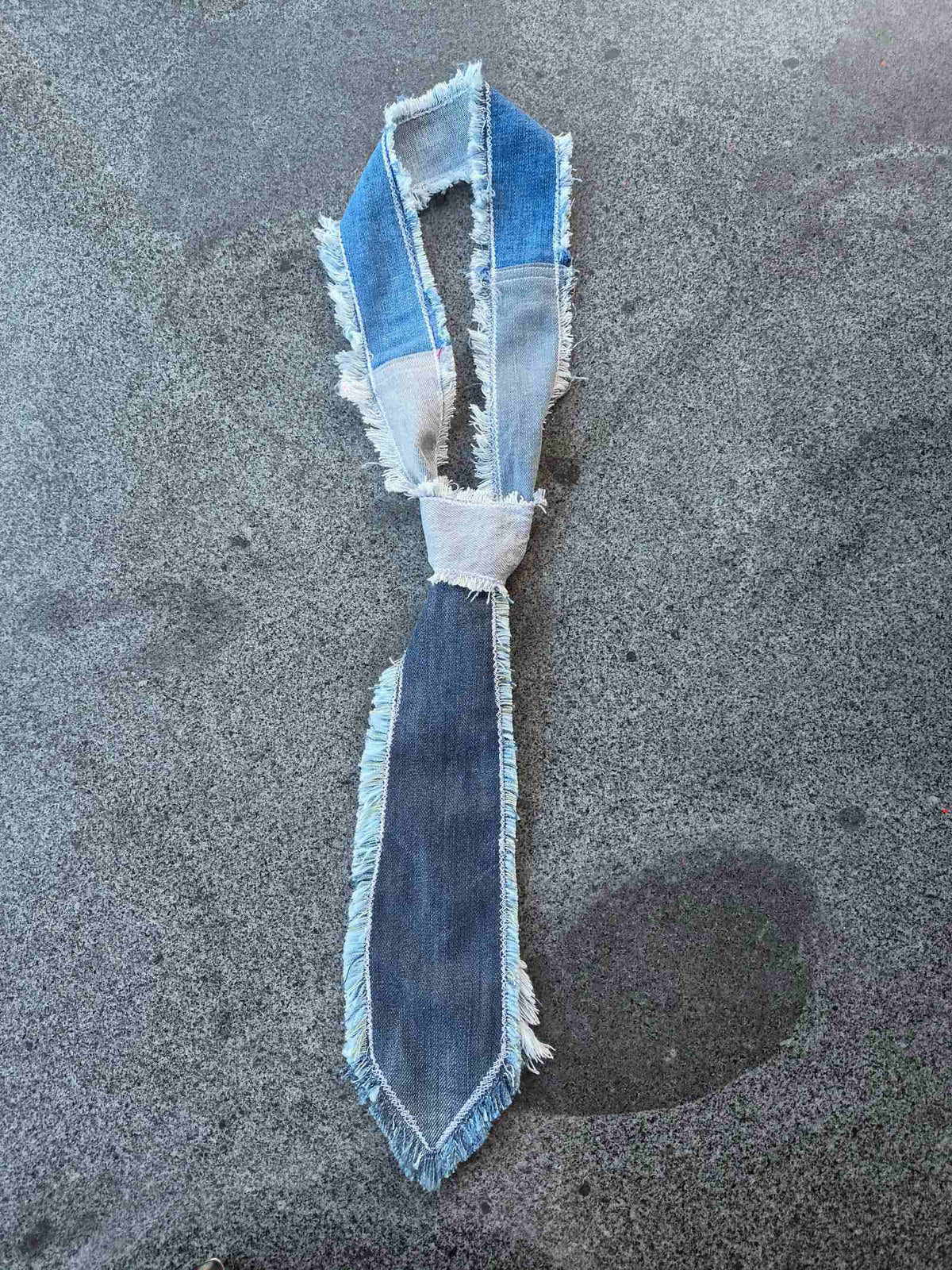 Upcycled denim stropdas opengelegd met patchwork halsband en rafelranden