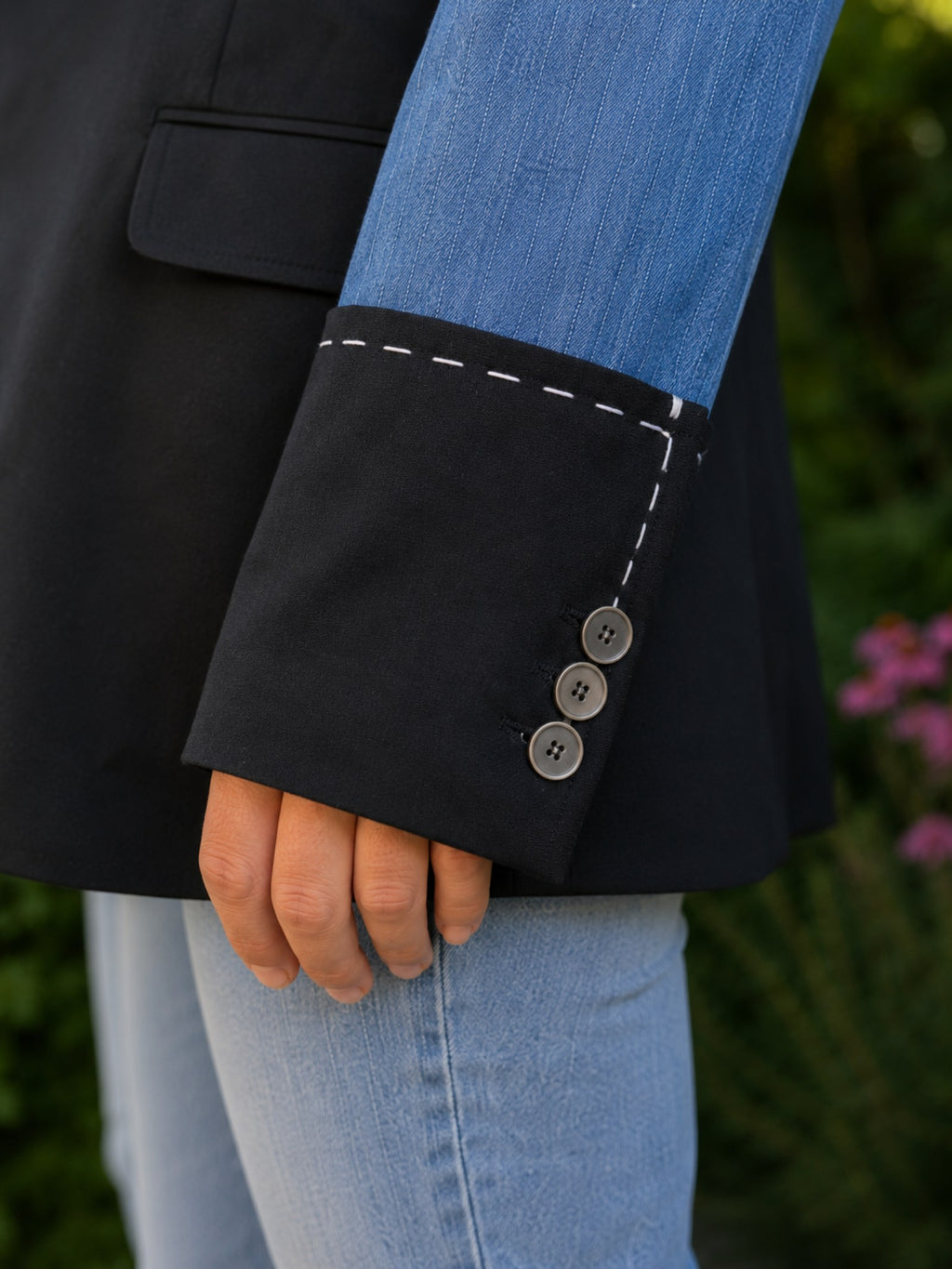 Detail van de denim manchet met witte handsteken en knoopjes op een handgemaakt upcycled denim colbert
