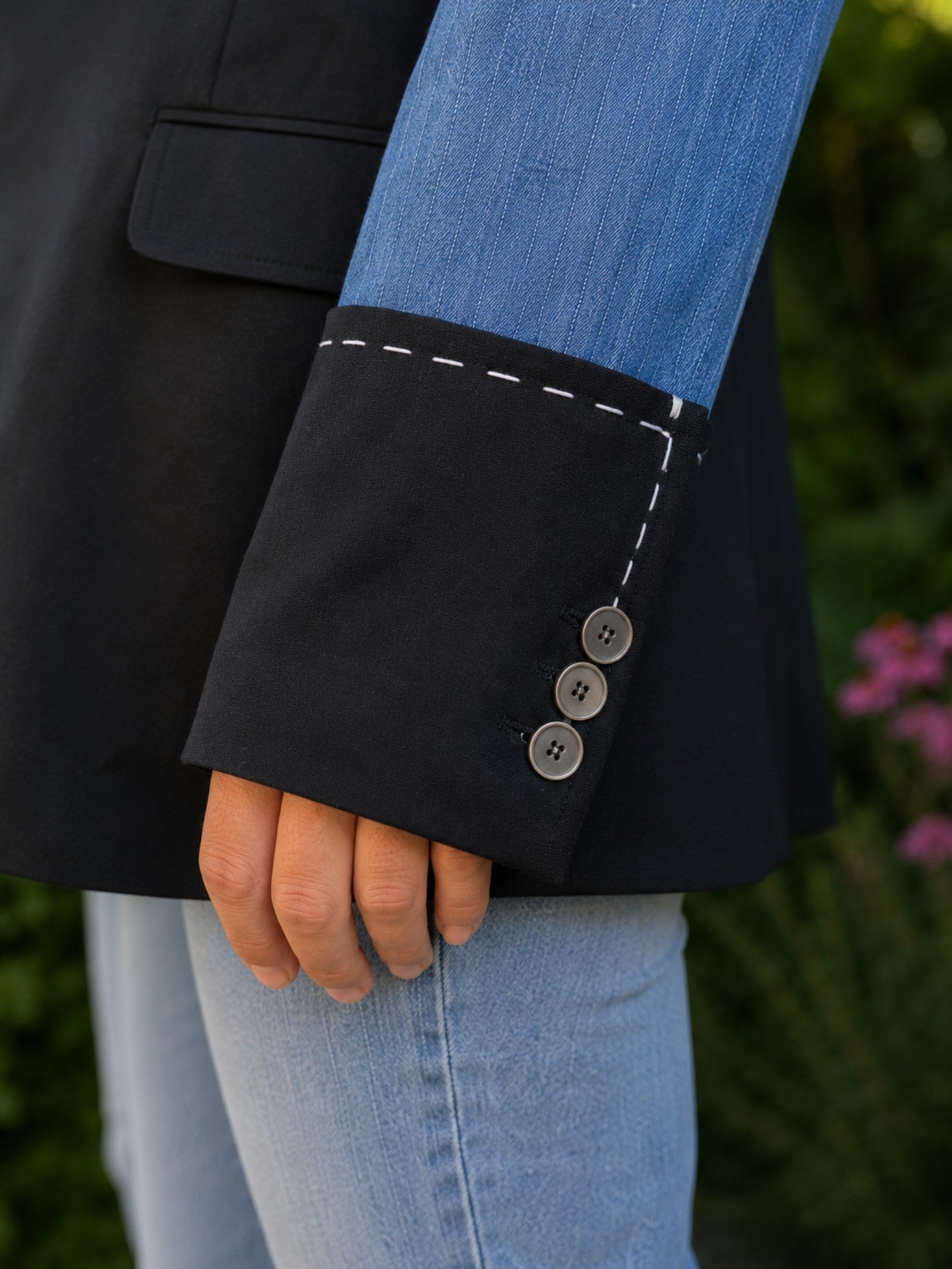 Detail van de denim manchet met witte handsteken en knoopjes op een handgemaakt upcycled denim colbert