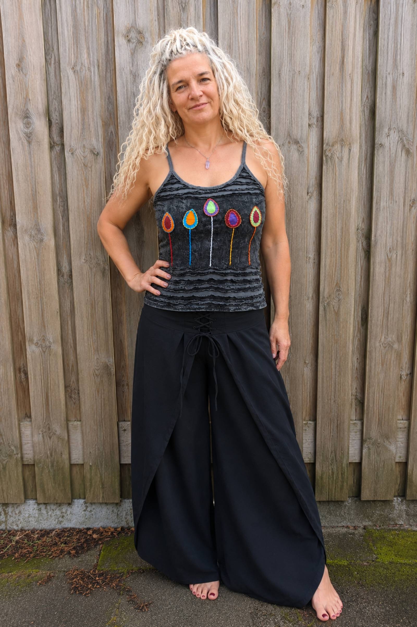 Model draagt handgemaakt boho topje met kleurrijke applicaties en zwarte omslagbroek van 100% katoen – Old New Atelier