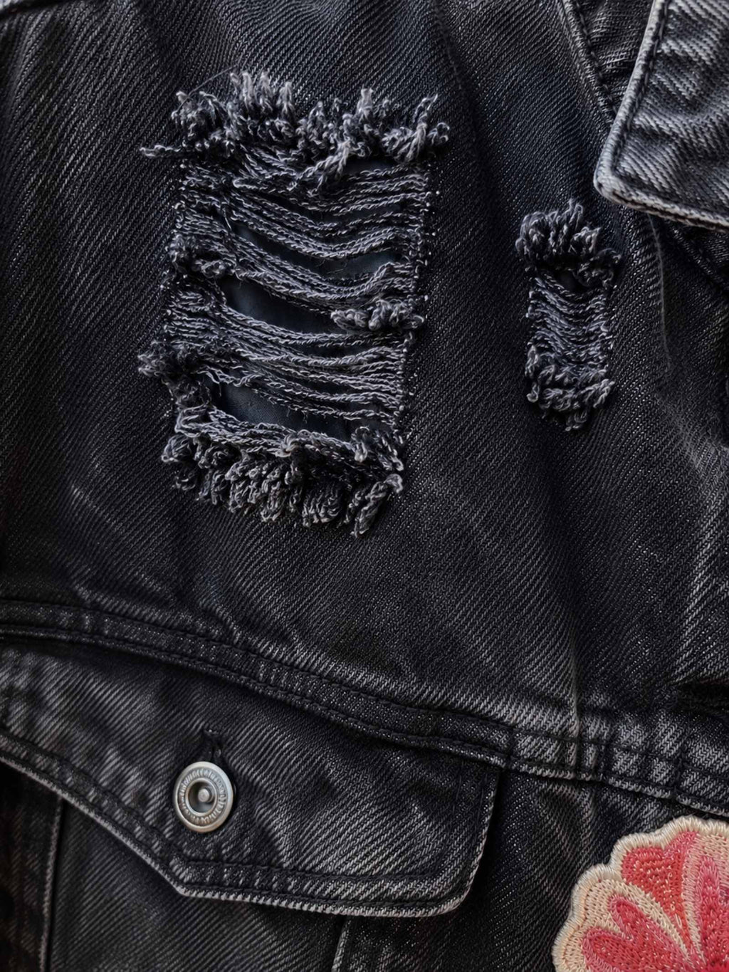 Close-up van distressed zwart denim met rafeldetails op een handgemaakt upcycled jasje van Old New Atelier.