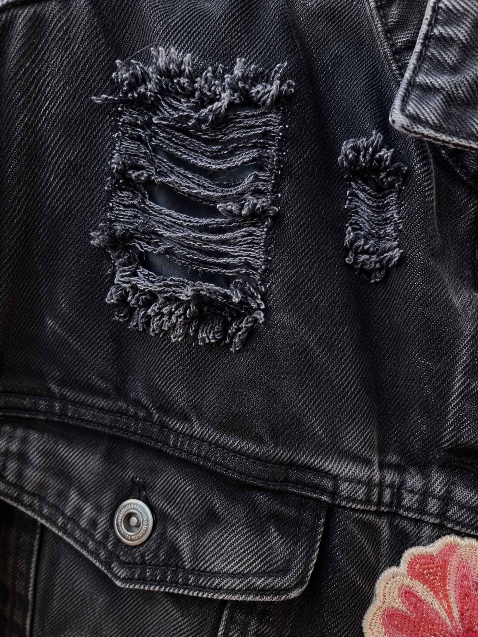 Close-up van distressed zwart denim met rafeldetails op een handgemaakt upcycled jasje van Old New Atelier.