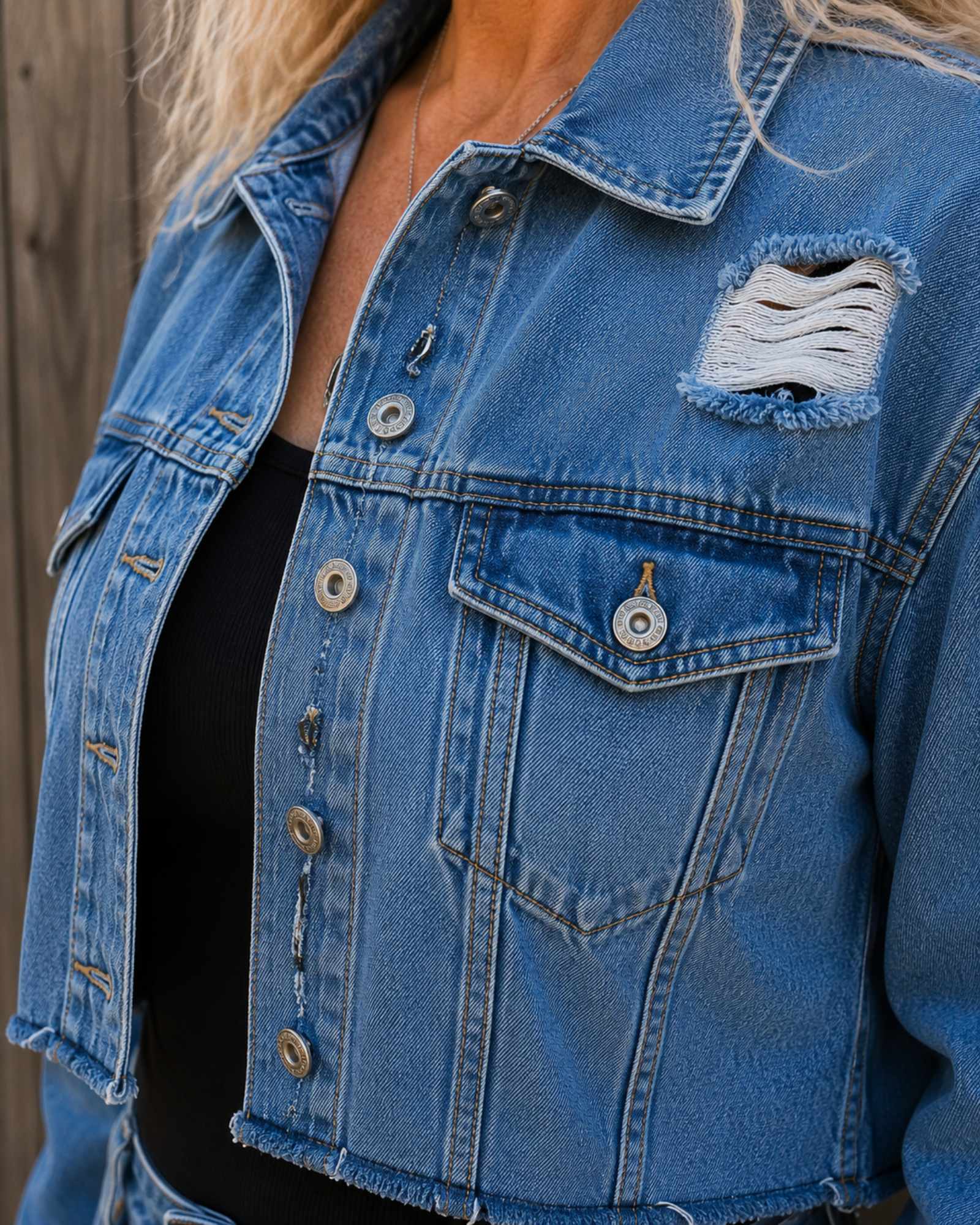 Detail van de borstzakjes, metalen knopen en distressed denim op een One of a Kind upcycled jeans crop jasje.