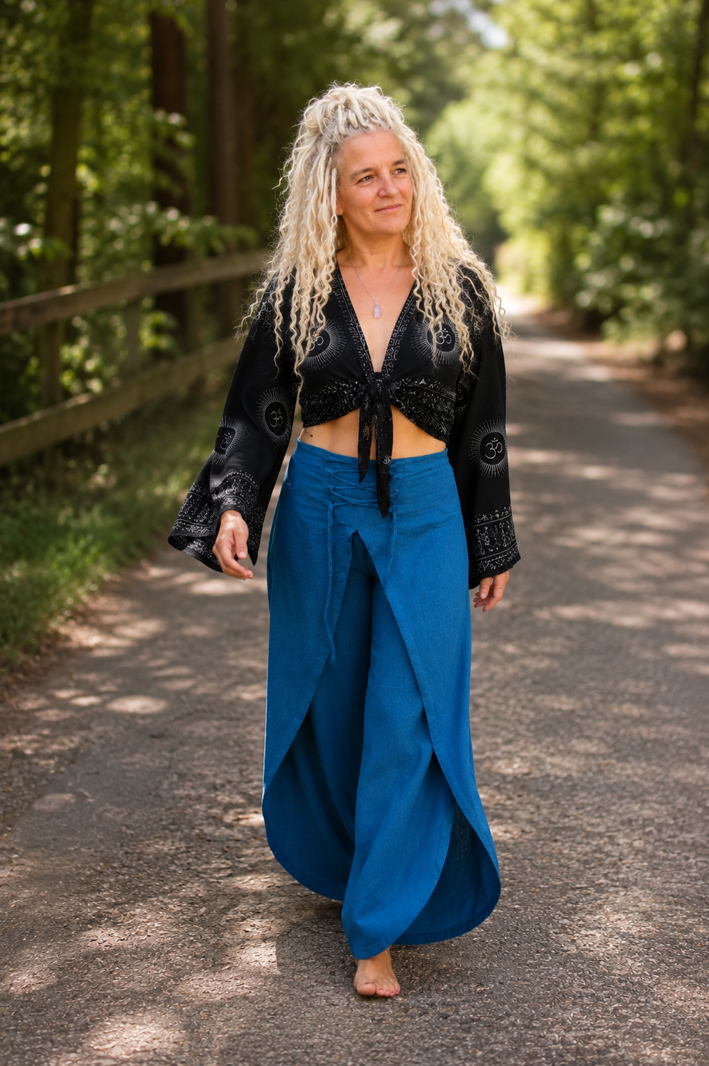 Model loopt in zwarte boho wikkelblouse met wijde mouwen en blauwe omslagbroek van 100% katoen – Old New Atelier