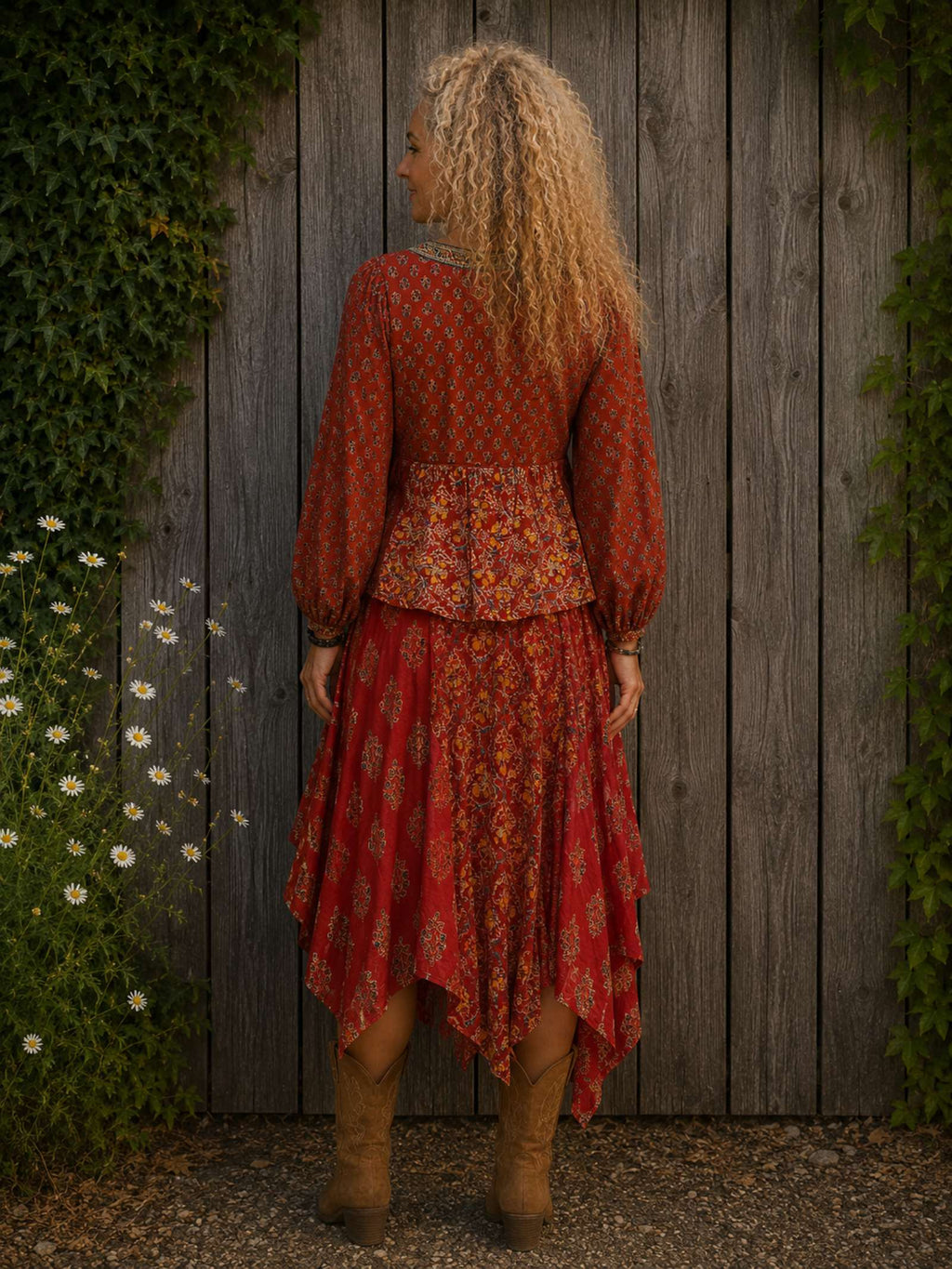 Achteraanzicht van een vrouwelijk model met rode asymmetrische boho rok en bijpassend boho blousje, gedragen met cowboylaarzen.