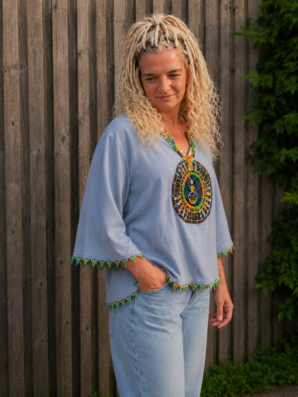 Zijaanzicht van de lichtblauwe boho blouse met handgemaakt kralenborduursel gedragen door model – Old New Atelier