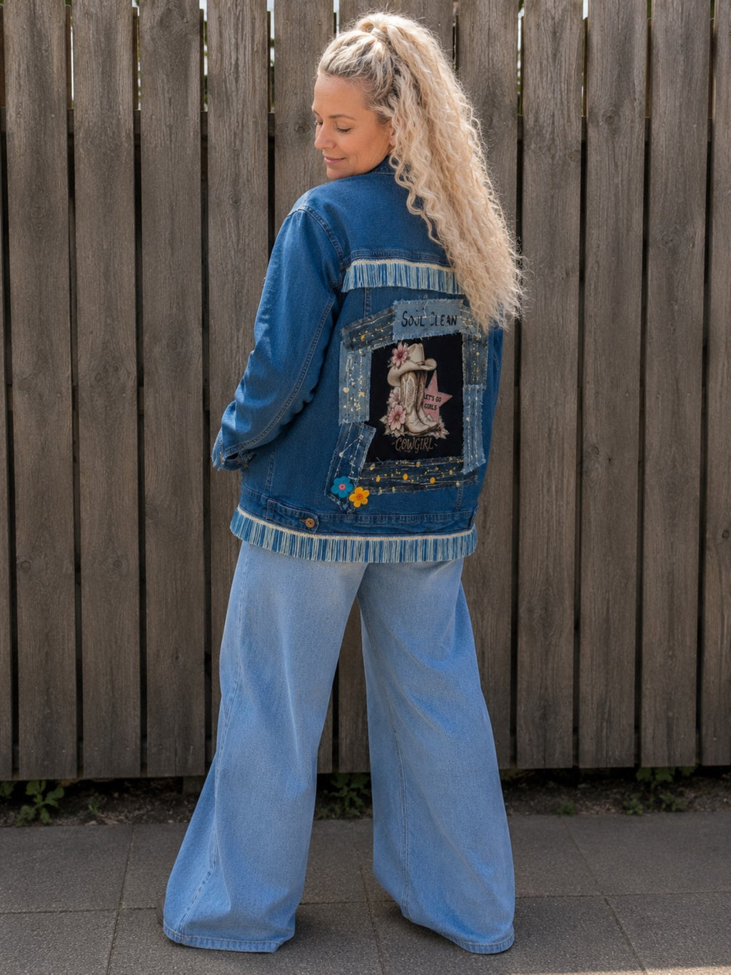 3/4 achteraanzicht van One of a Kind upcycled denim jasje met Cowgirl artwork, denim patchwork en franjes gedragen door model
