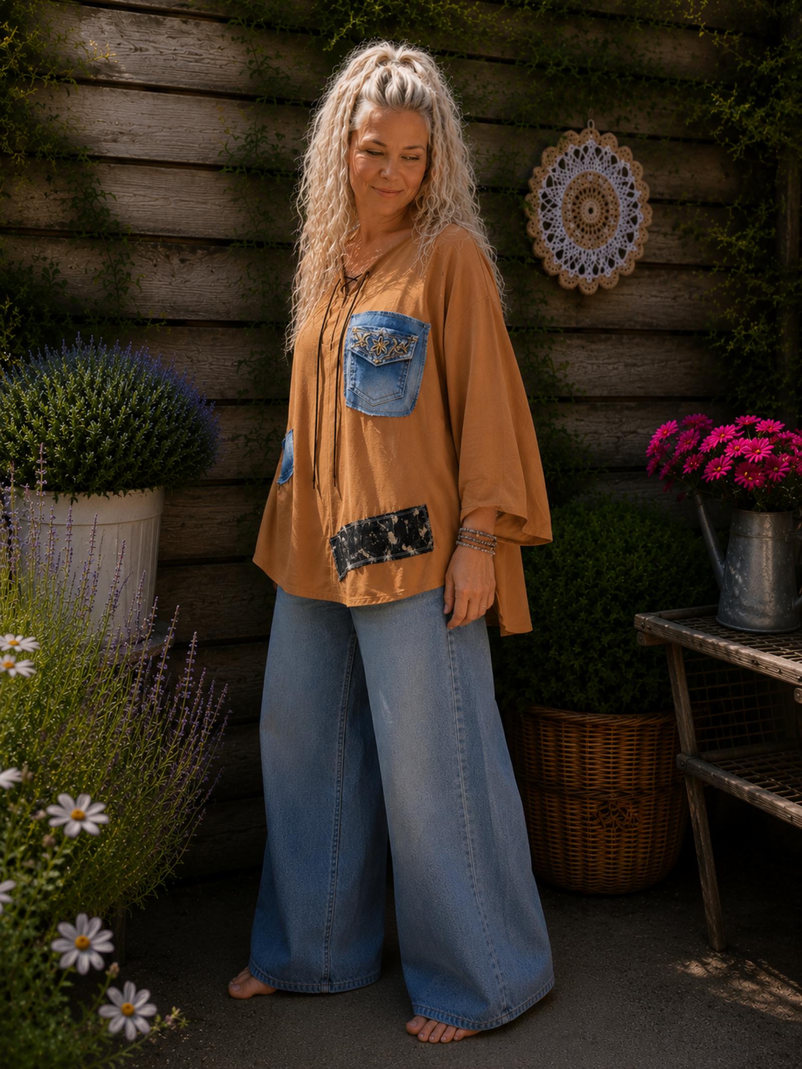 3/4 zijaanzicht van handgemaakte oversized camel blouse met upcycled denim details gedragen door model