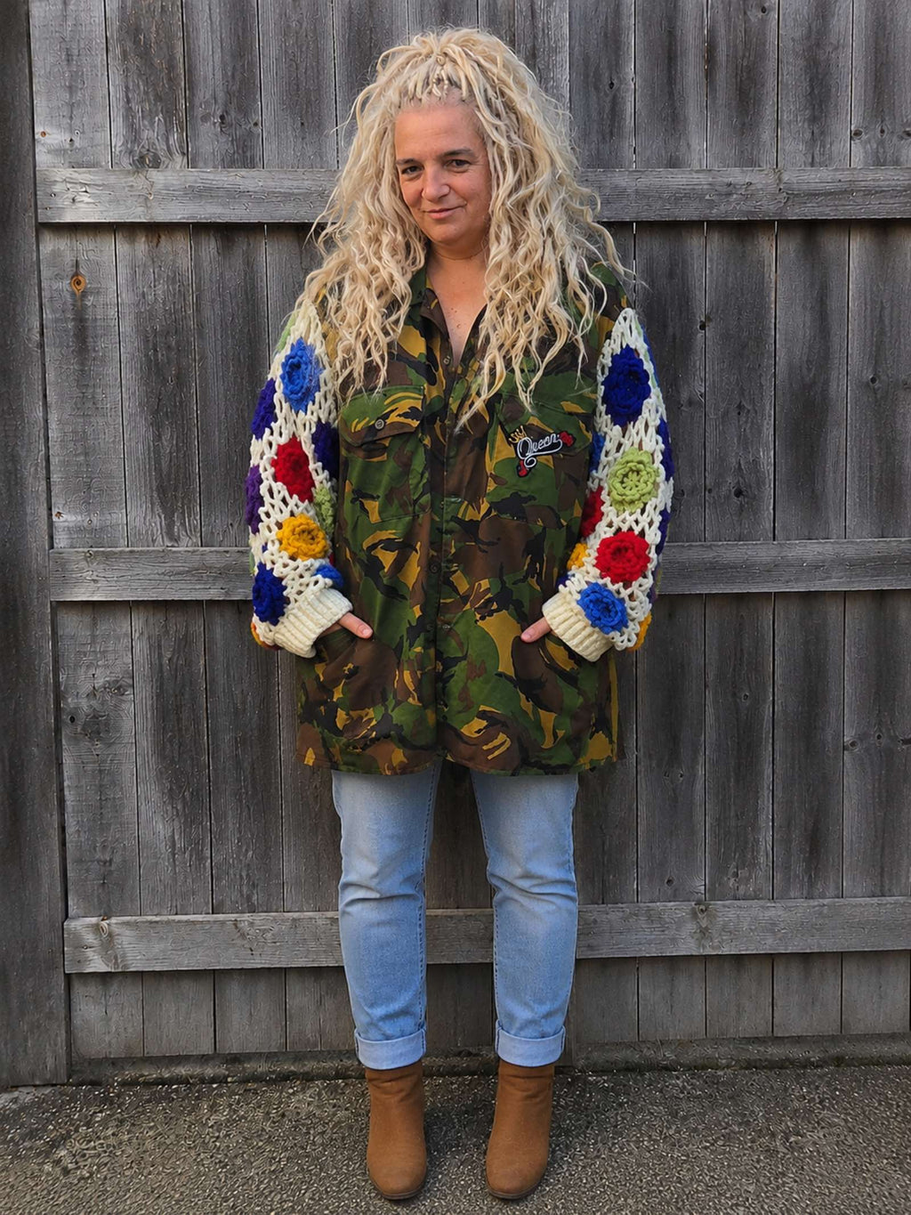 Handgemaakte upcycled camouflage jas met gehaakte bloemenmouwen en oversized pasvorm, voorkant gedragen door model.