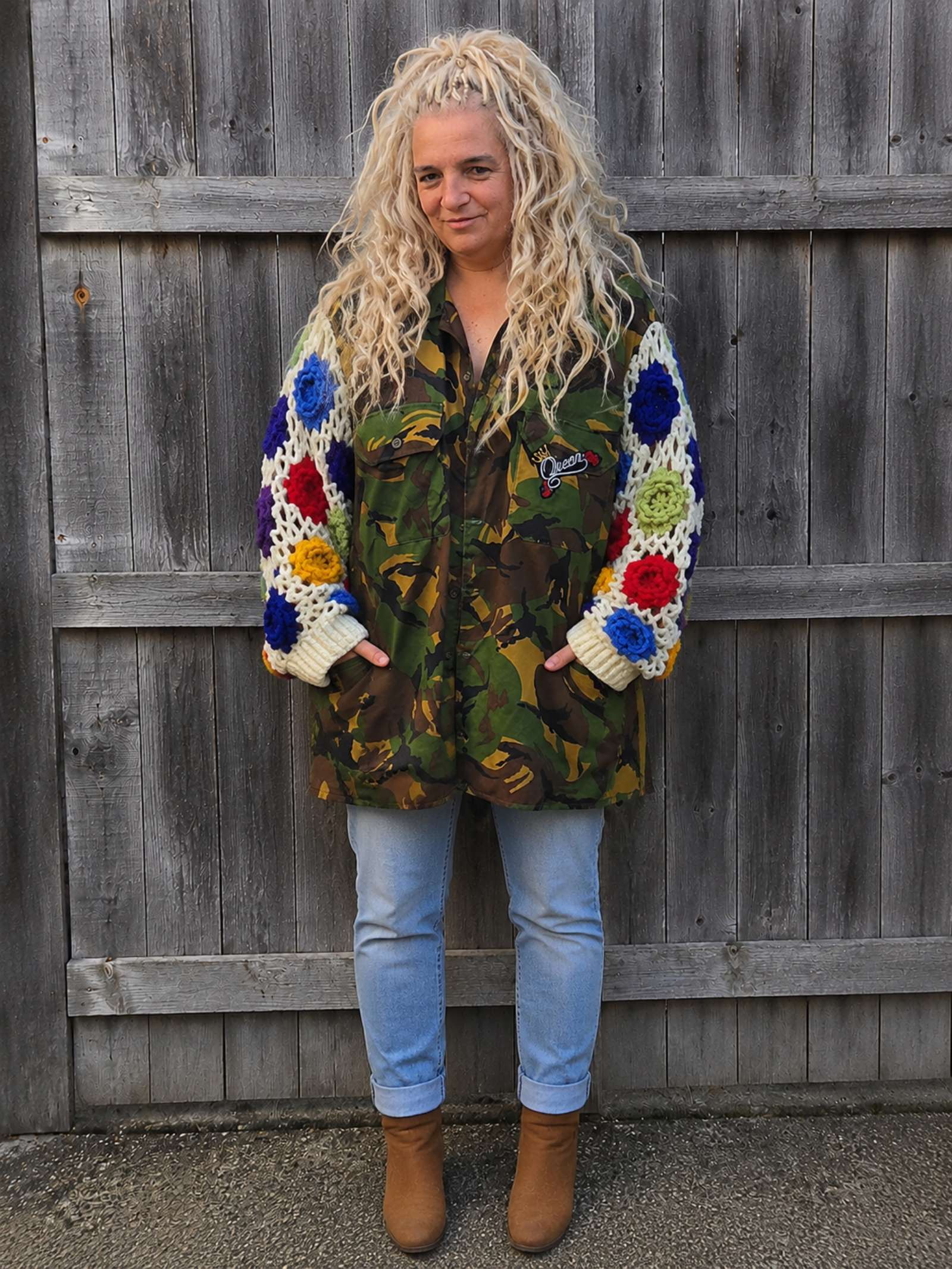 Handgemaakte upcycled camouflage jas met gehaakte bloemenmouwen en oversized pasvorm, voorkant gedragen door model.
