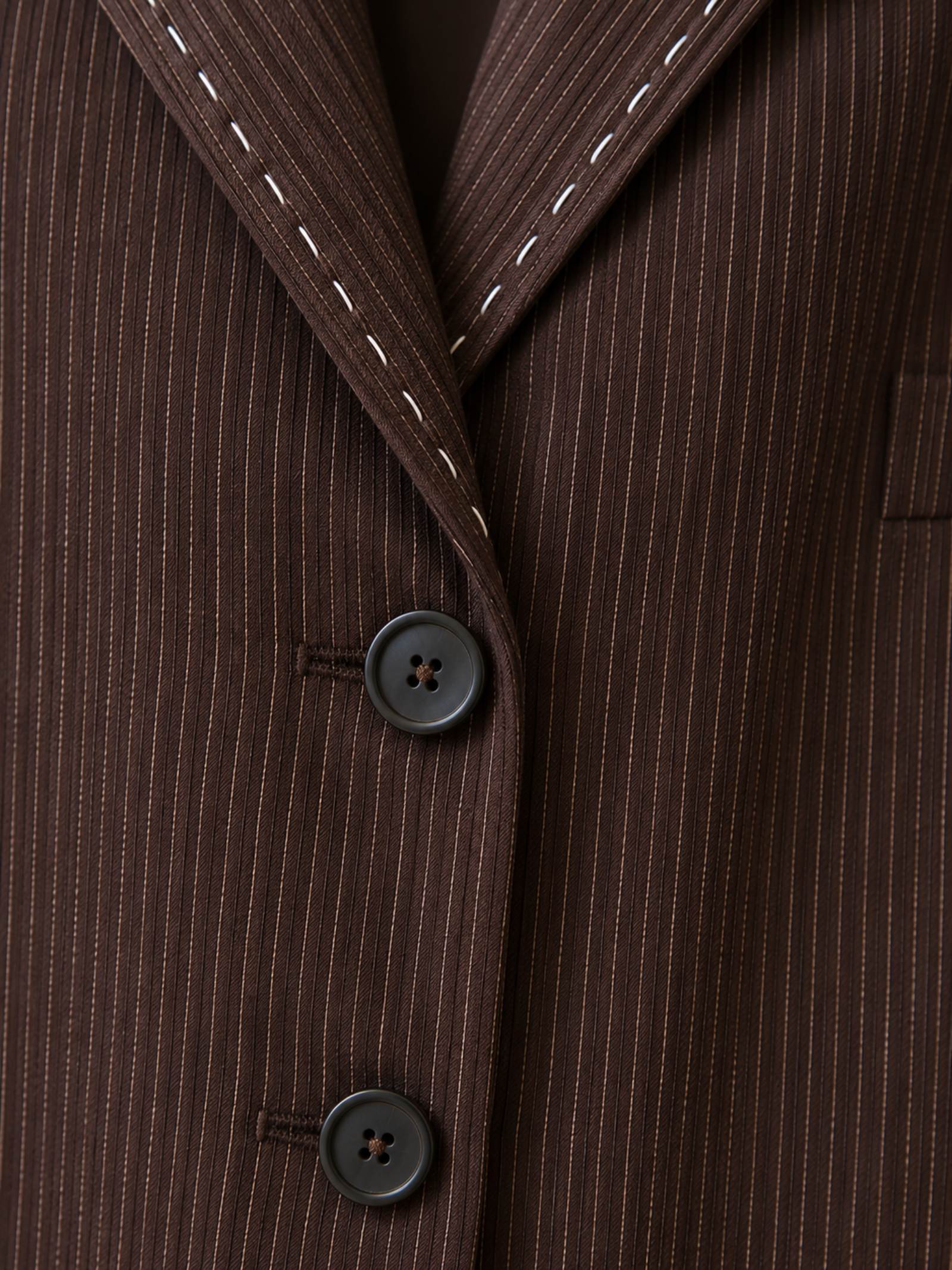Close-up van bruine ribstof, revers en handgestikte details.