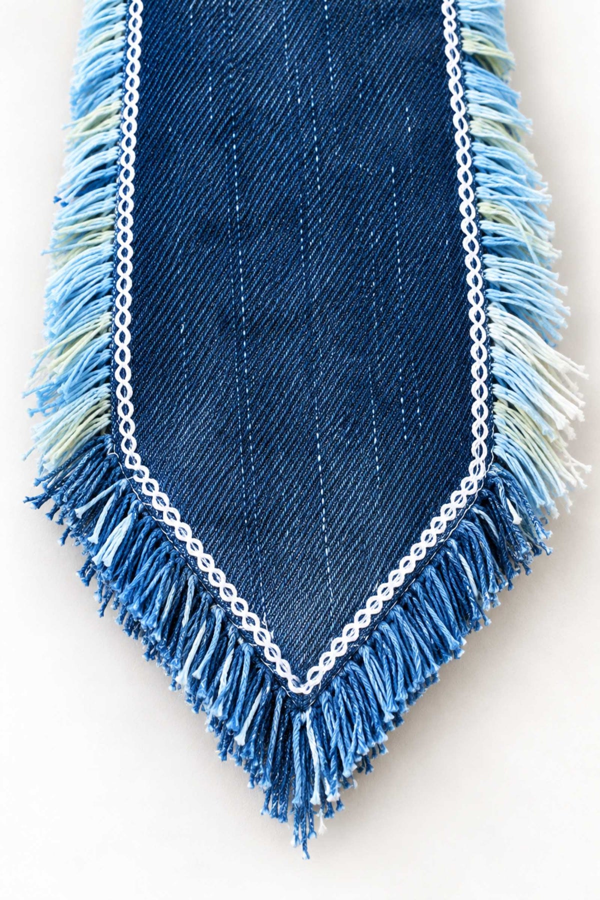 Close-up van donkerblauwe denim stropdaspunt met stiksels en rafelranden
