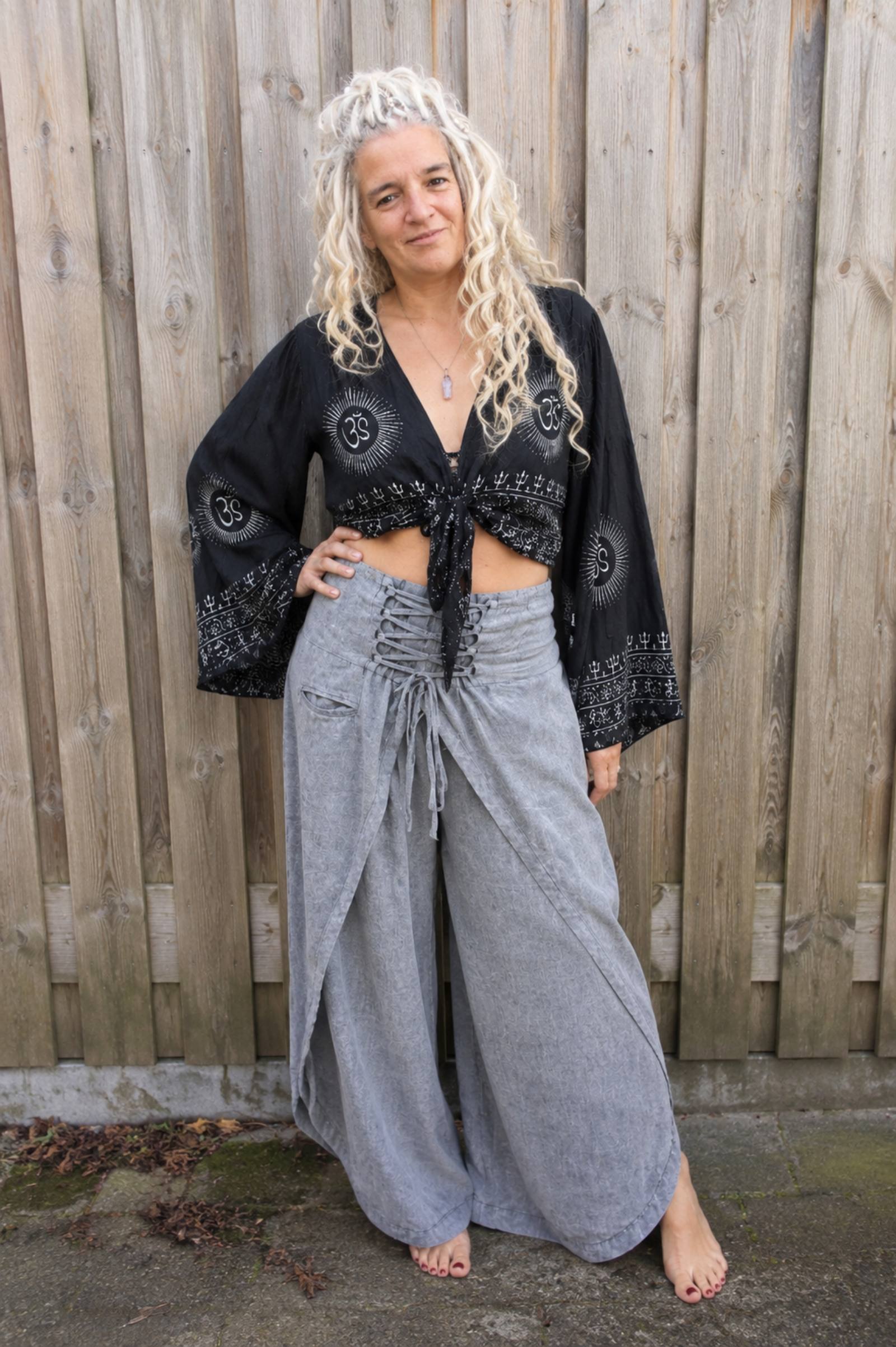 Model draagt zwarte boho wikkelblouse met wijde mouwen en grijze omslagbroek van 100% katoen – Old New Atelier