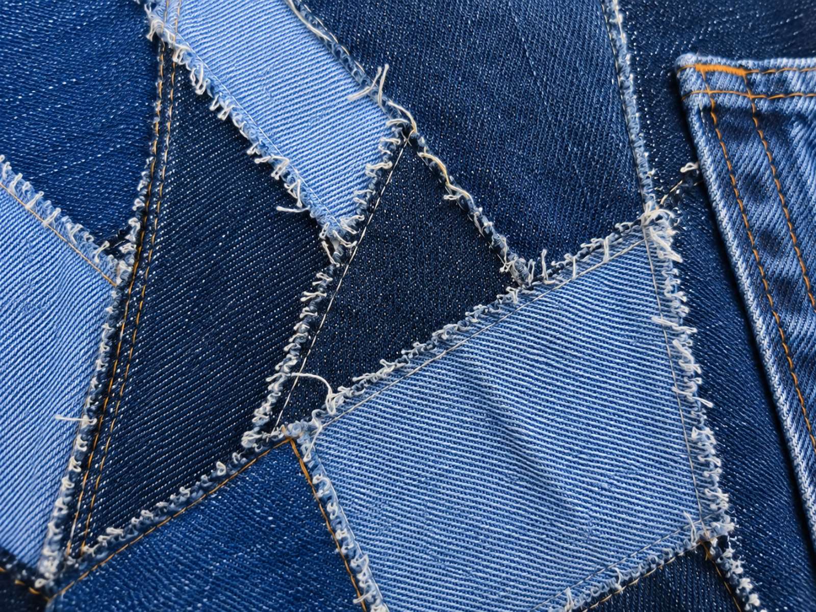 Close-up van de denimstructuur, stiksels en rafelranden van het Levi's patchwork hesje.