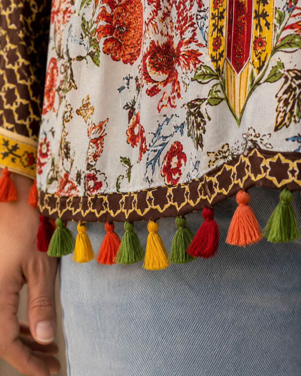 Detail van kleurrijke kwastjes langs de zoom van de boho blouse