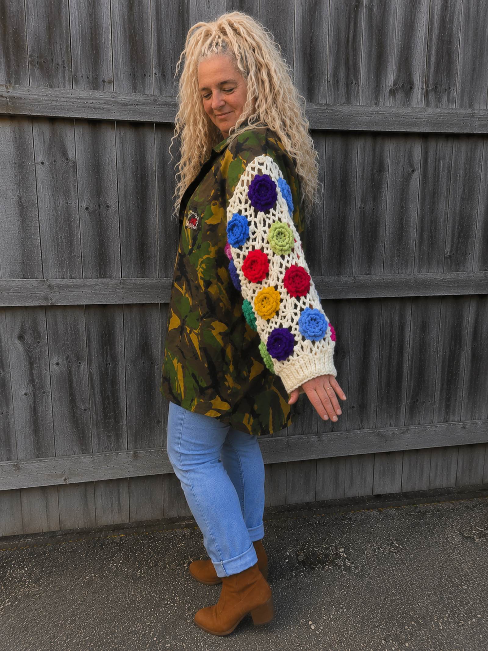 Zijaanzicht van een upcycled camouflage jas met opvallende gehaakte bloemenmouwen en oversized pasvorm.
