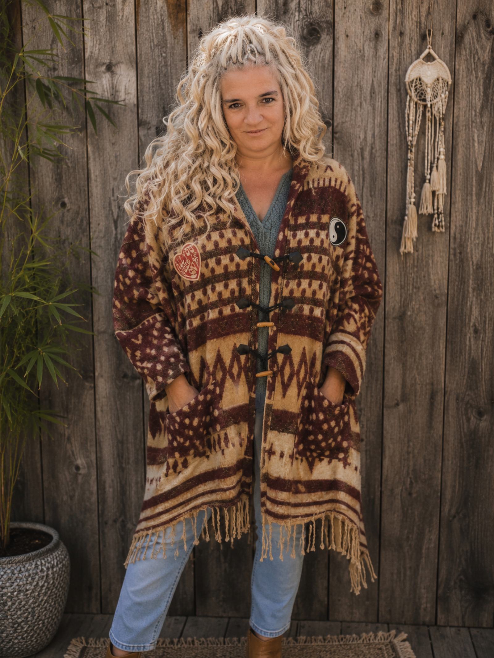 Vrouwelijk model draagt een oversized boho poncho met capuchon, franjes en Buddha details van Old New Atelier.