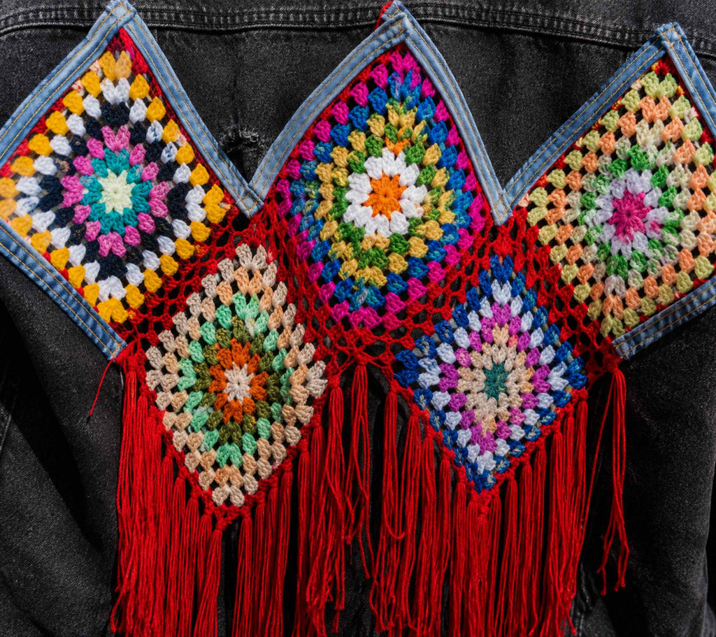 Close-up van het handgehaakte kleurrijke kunstwerk op de achterkant van het denim jasje.