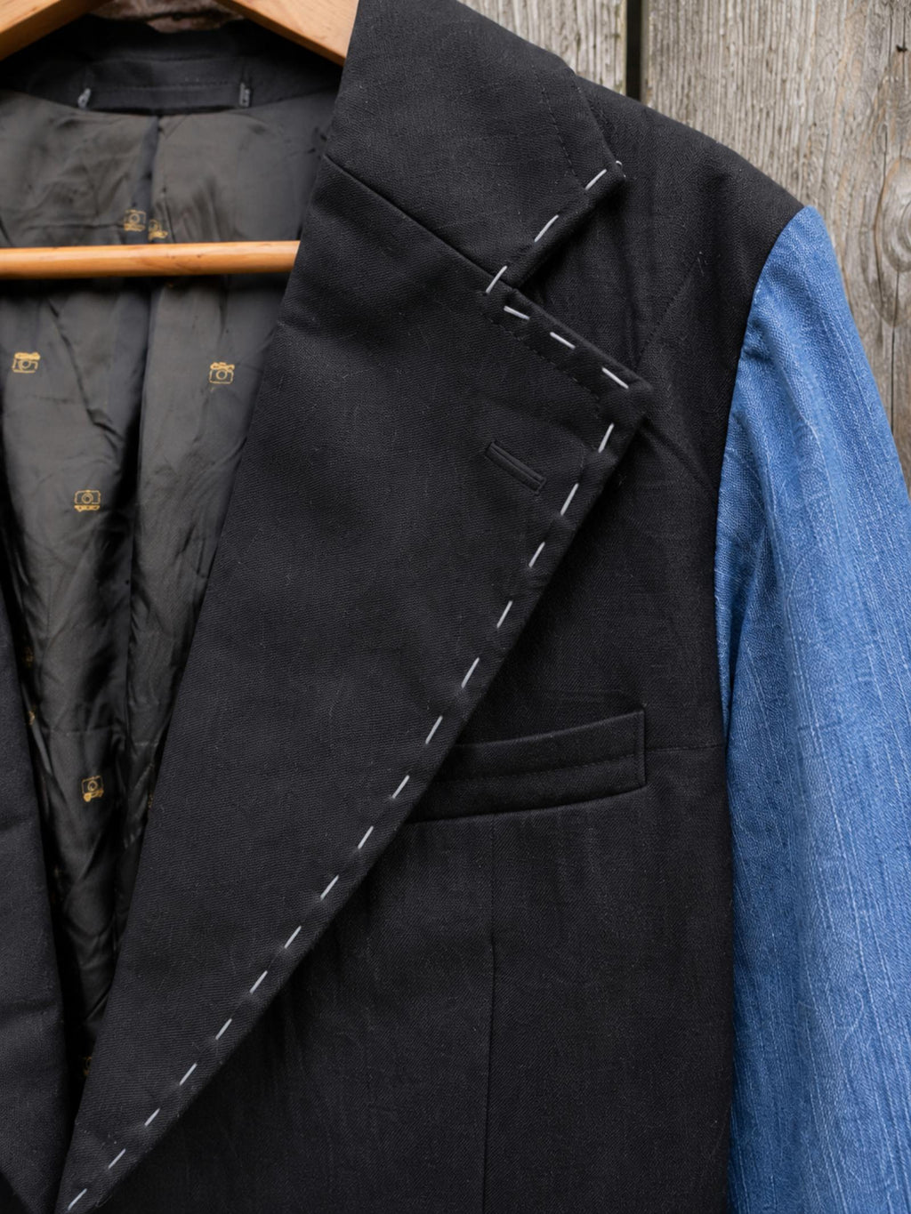 Close-up van de revers met handgestikte witte siersteken op een handgemaakt upcycled denim colbert