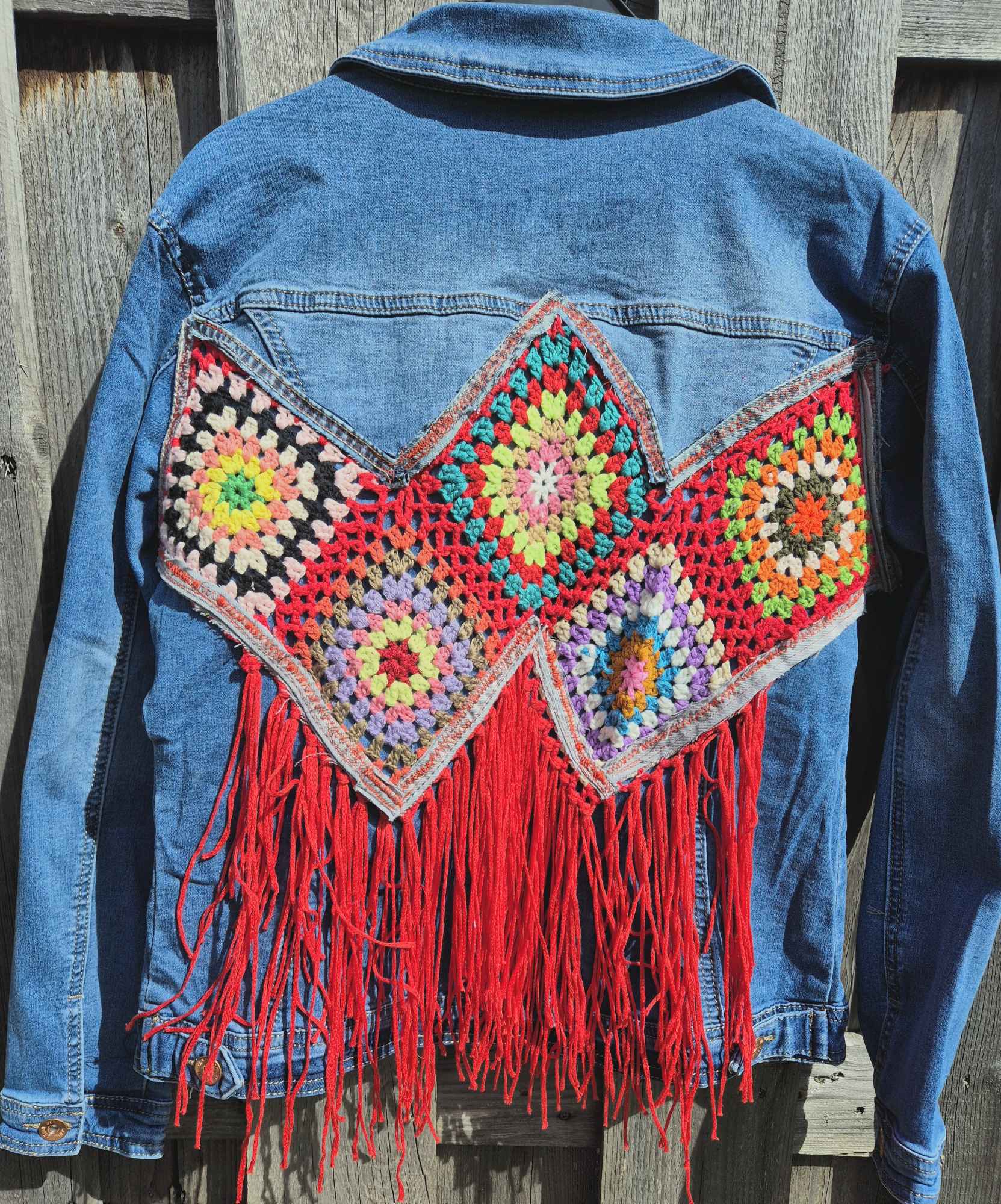 Volledige achterkant van upcycled denim jasje met kleurrijke crochet panelen en franjes – one of a kind